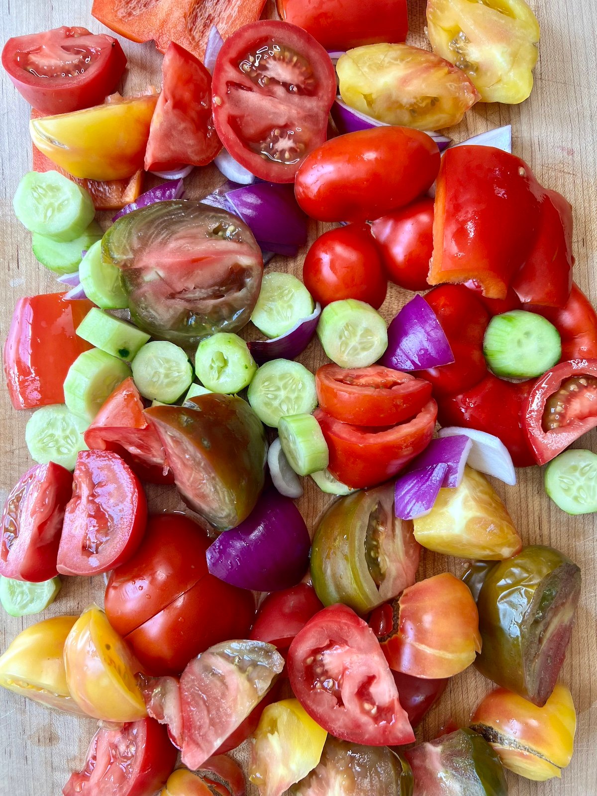 Chopped gazpacho ingredients on cutting board.