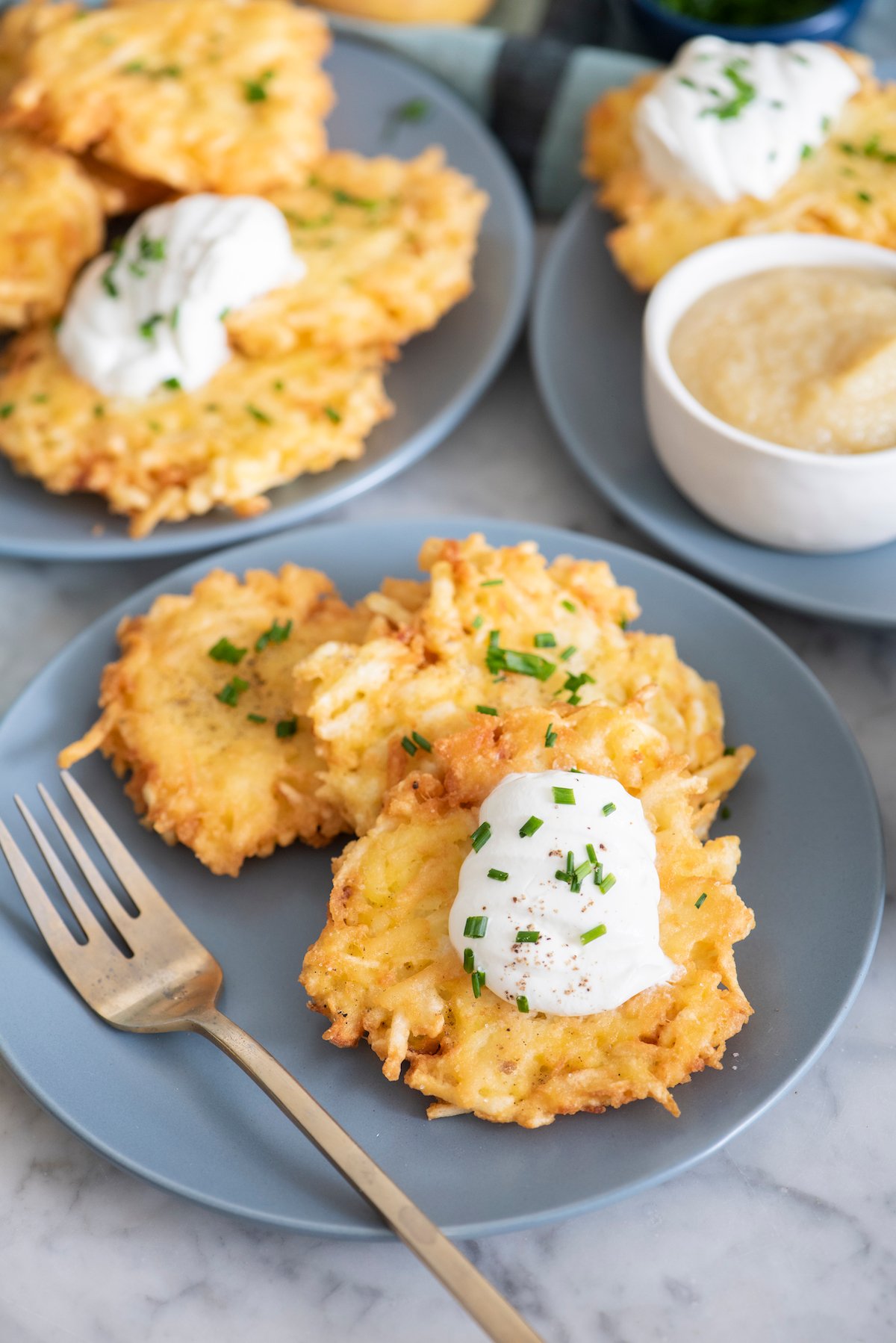 Potato Latkes on blue plate topped with sour cream and chives.