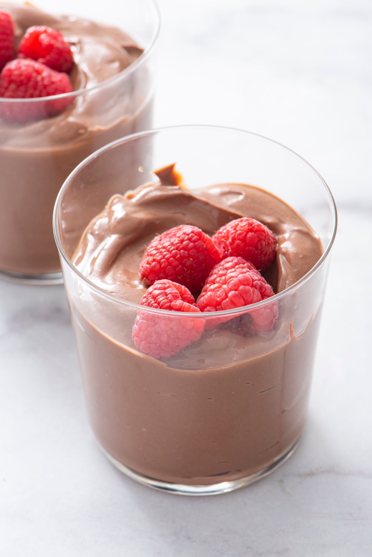 Chocolate Tofu Pudding in clear serving class topped with raspberries.