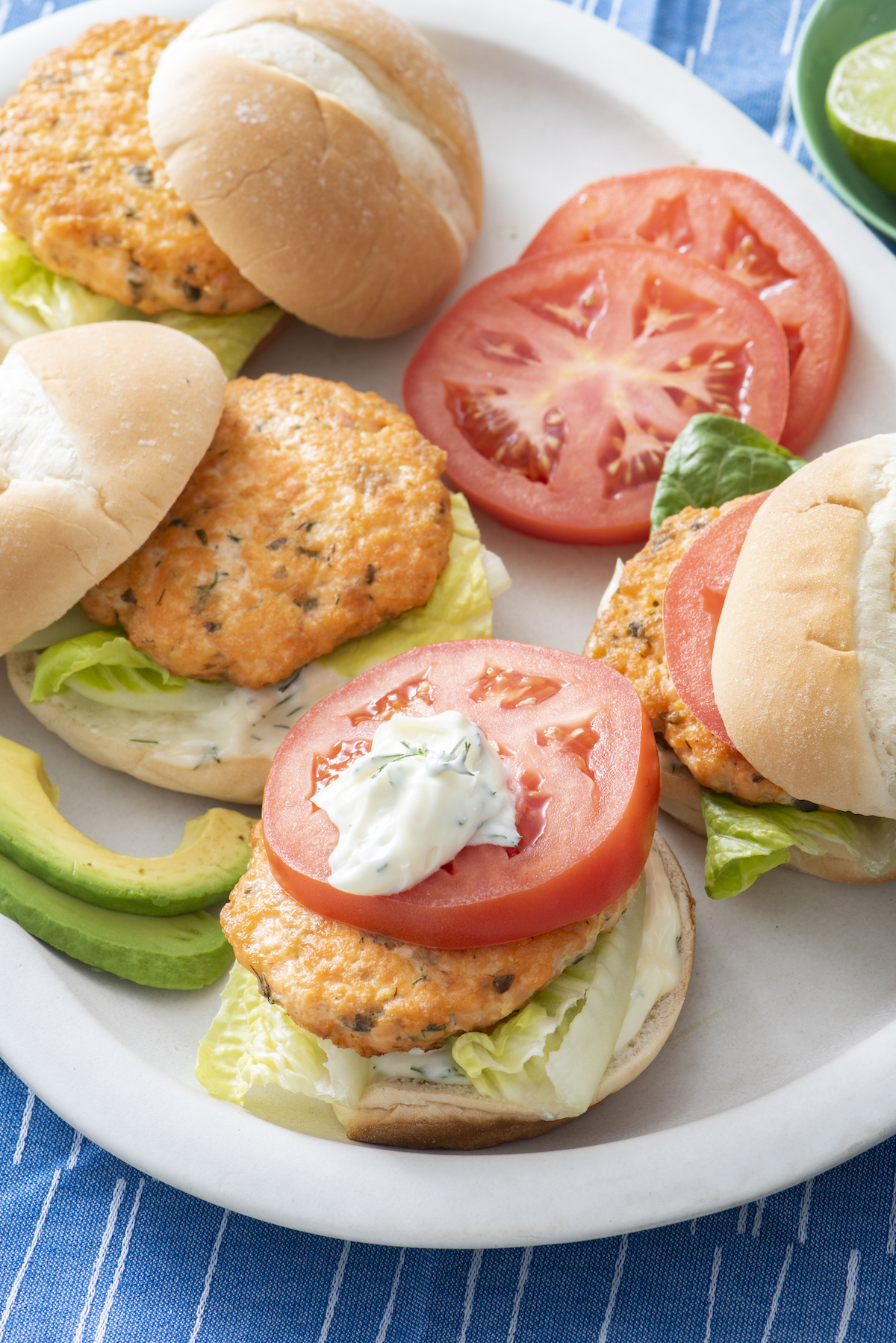 Open faced salmon burger topped with tomato and dollop of lemon yogurt sauce.
