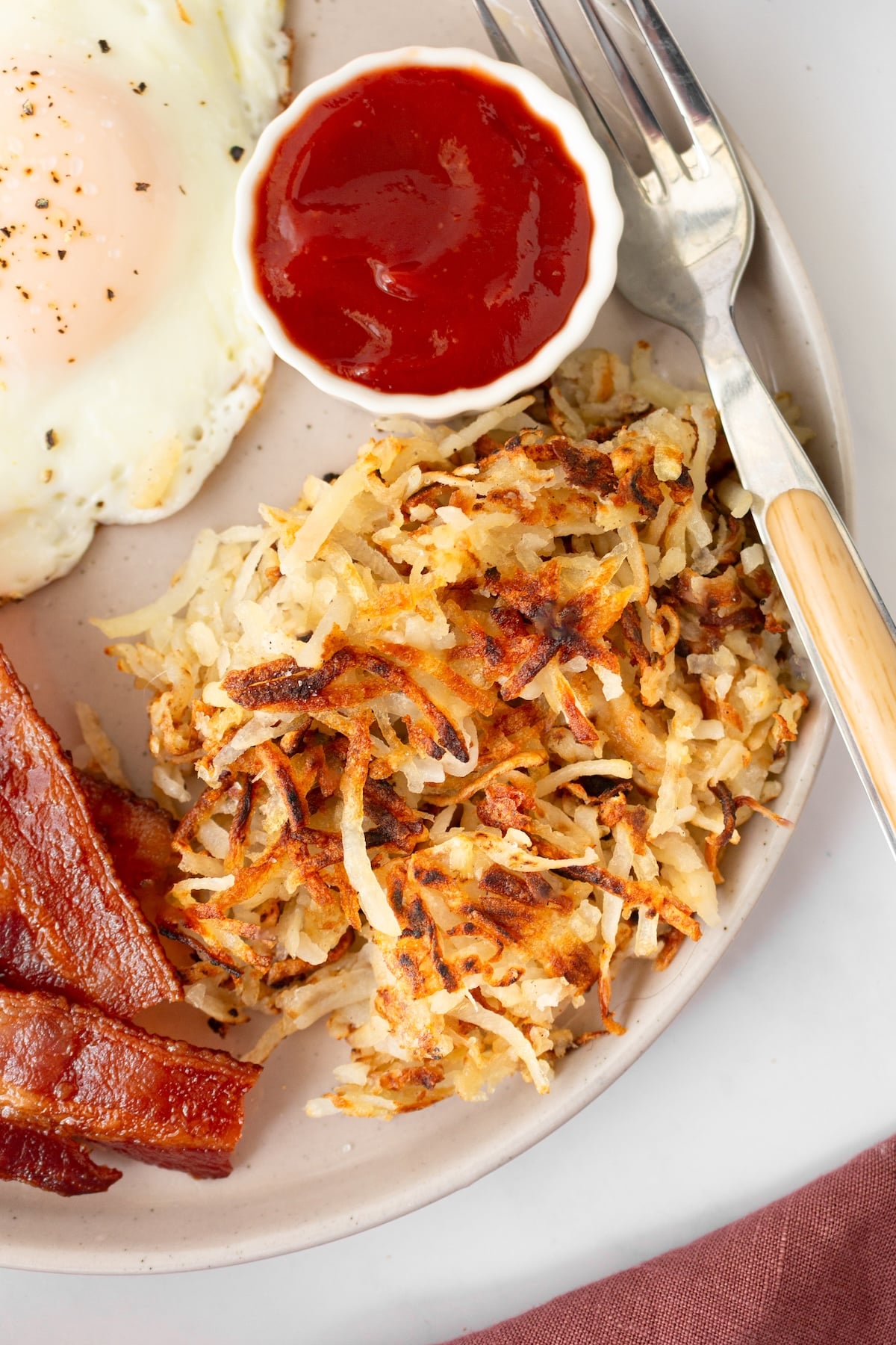 Crispy homemade hash browns with a side of ketchup. Serve with bacon and eggs.