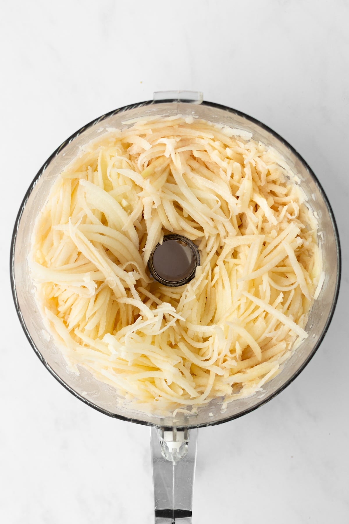 Shredded potatoes in a food processor.