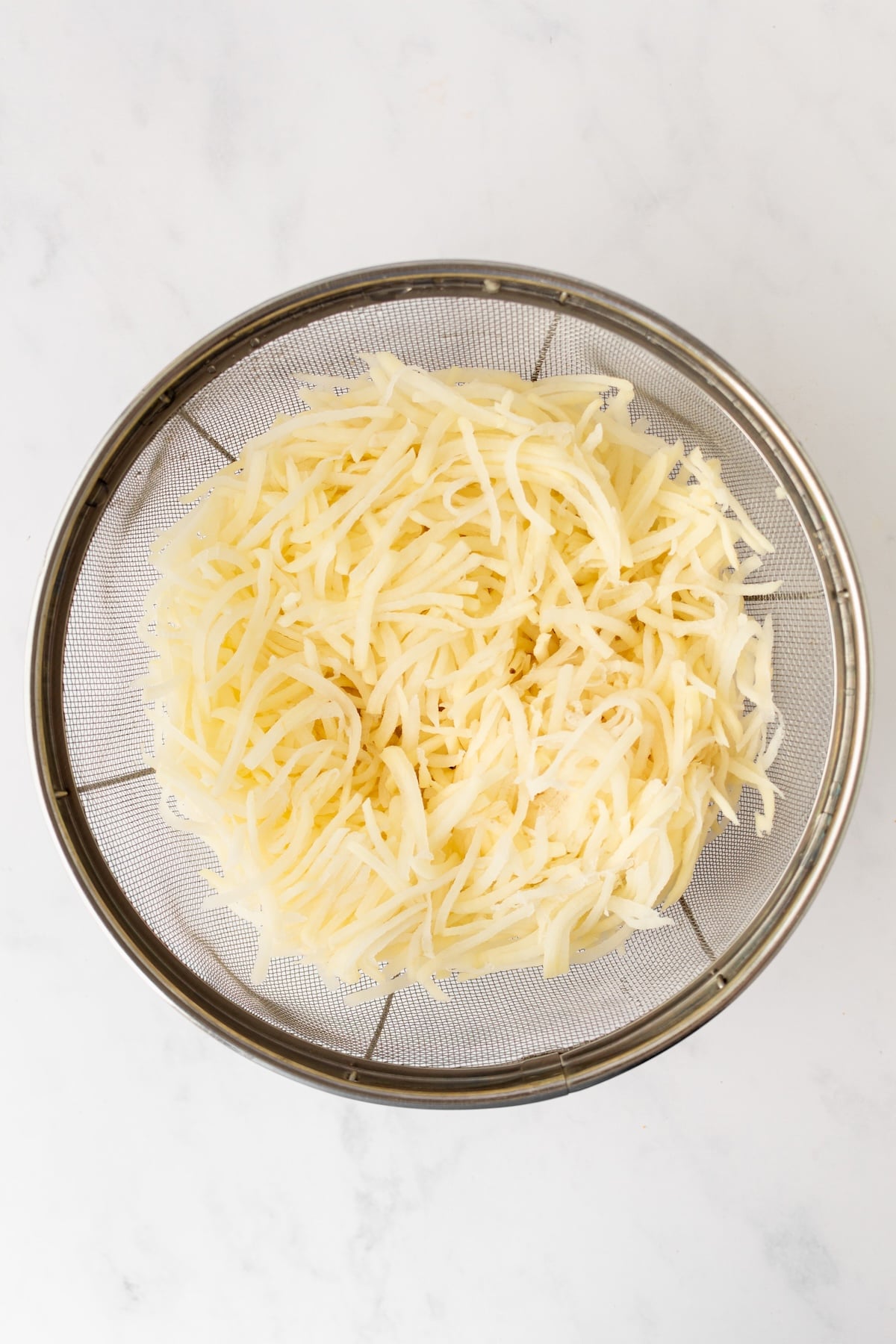 Shredded potatoes in a colander.