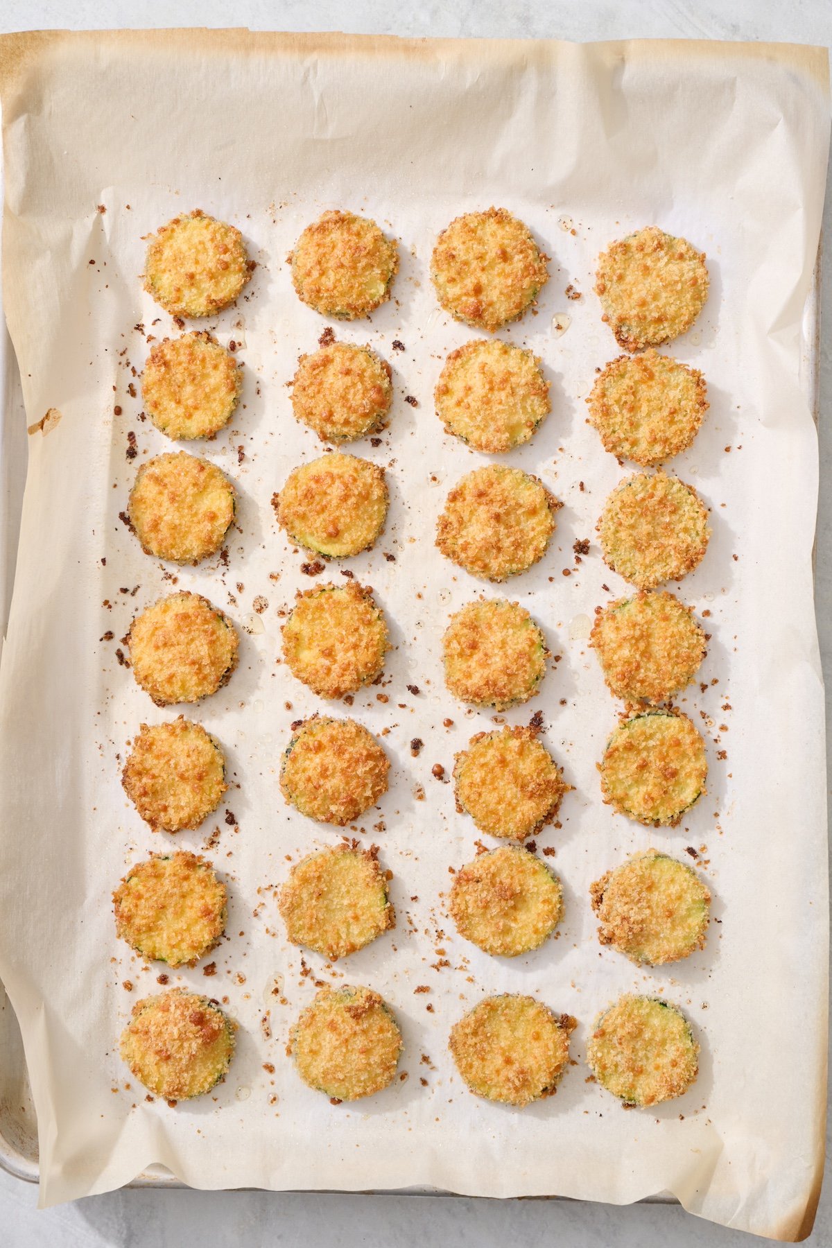 Baked zucchini coins on baking sheet.