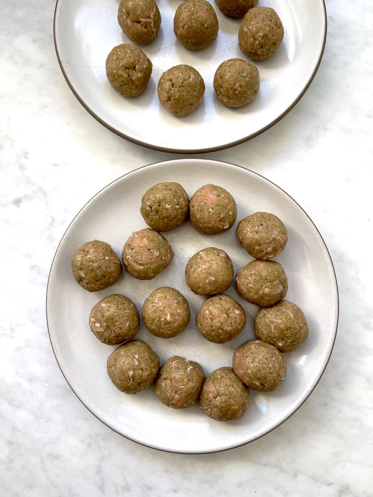 Formed, uncooked Turkey Pesto Meatballs on plates.