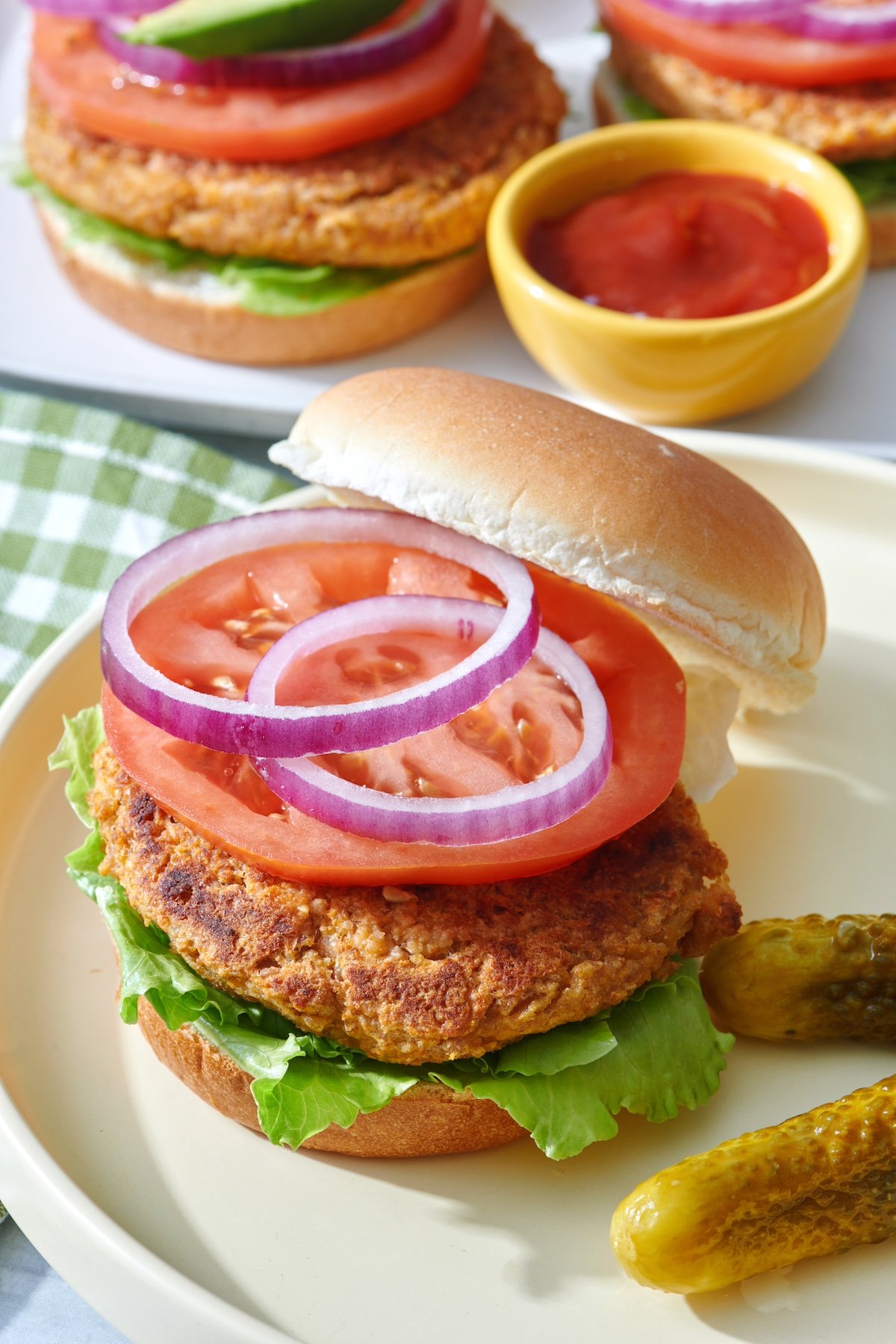The best veggie burger topped with lettuce, onion and tomato on a serving plate. 