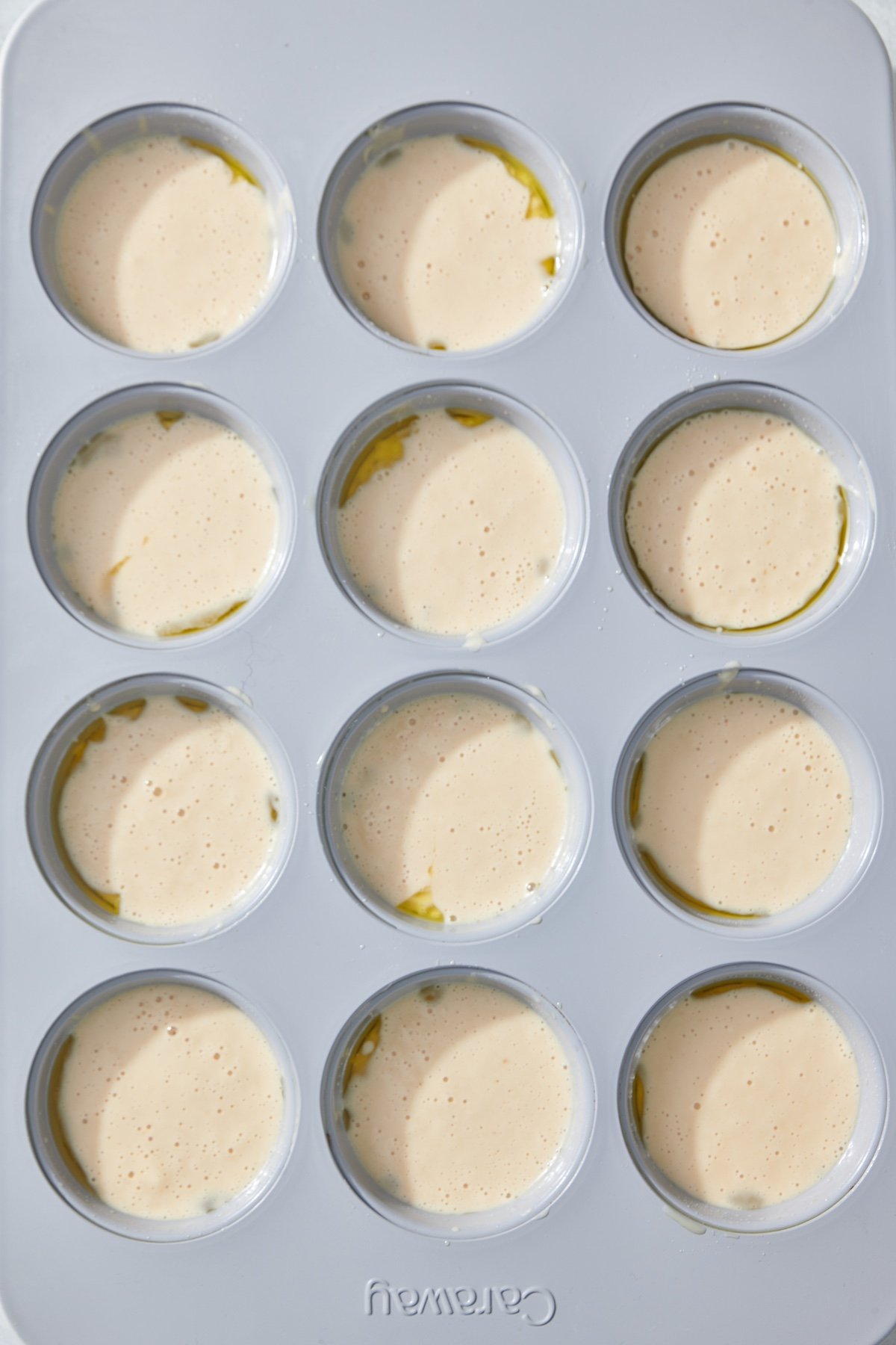 a 12 cup muffin tin with batter in each well.