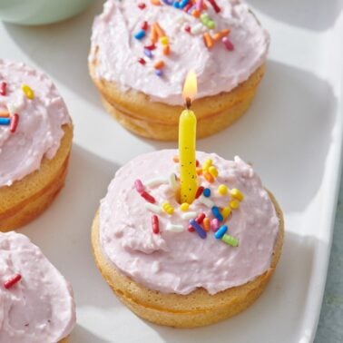 Breakfast Cupcake wit pink frosting, rainbow color sprinkles and birthday candle in the center.