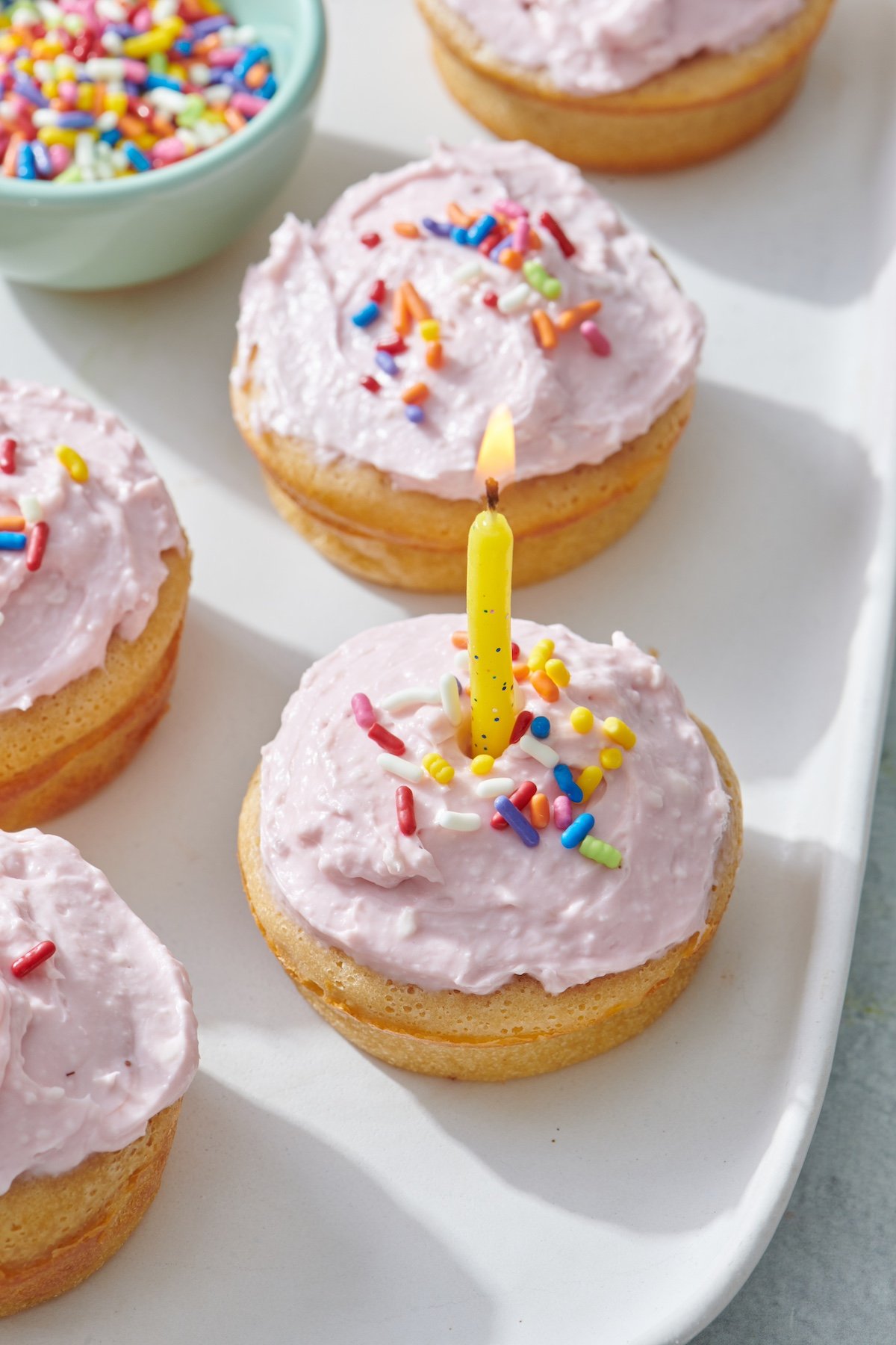 Breakfast Cupcake wit pink frosting, rainbow color sprinkles and birthday candle in the center.