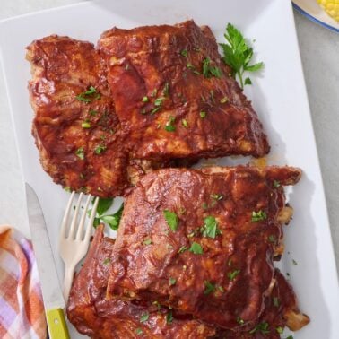 Tender slow cooker ribs on a white serving platter.