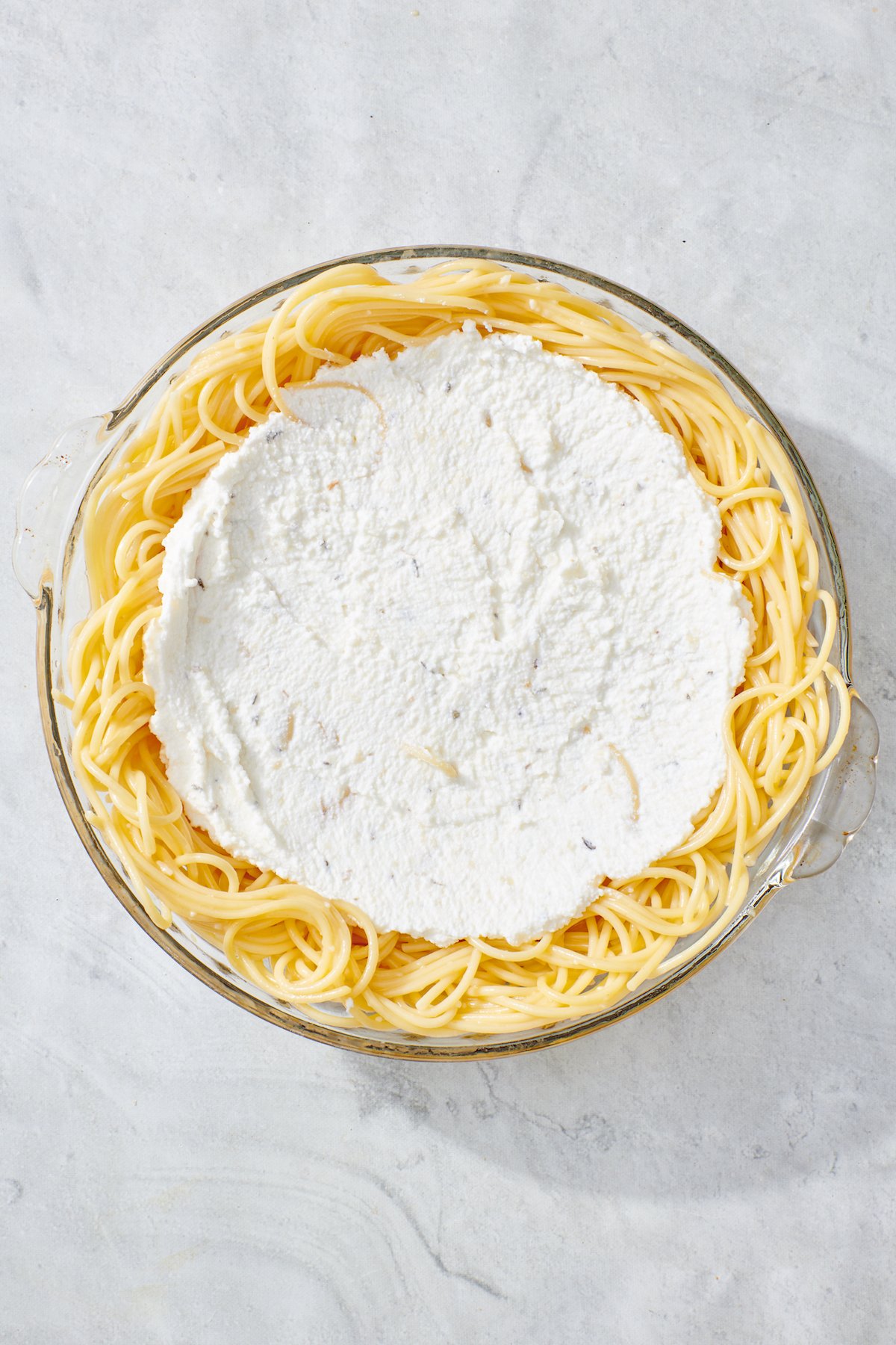 Ricotta cheese mixture layered of spaghetti noodles in pie dish.