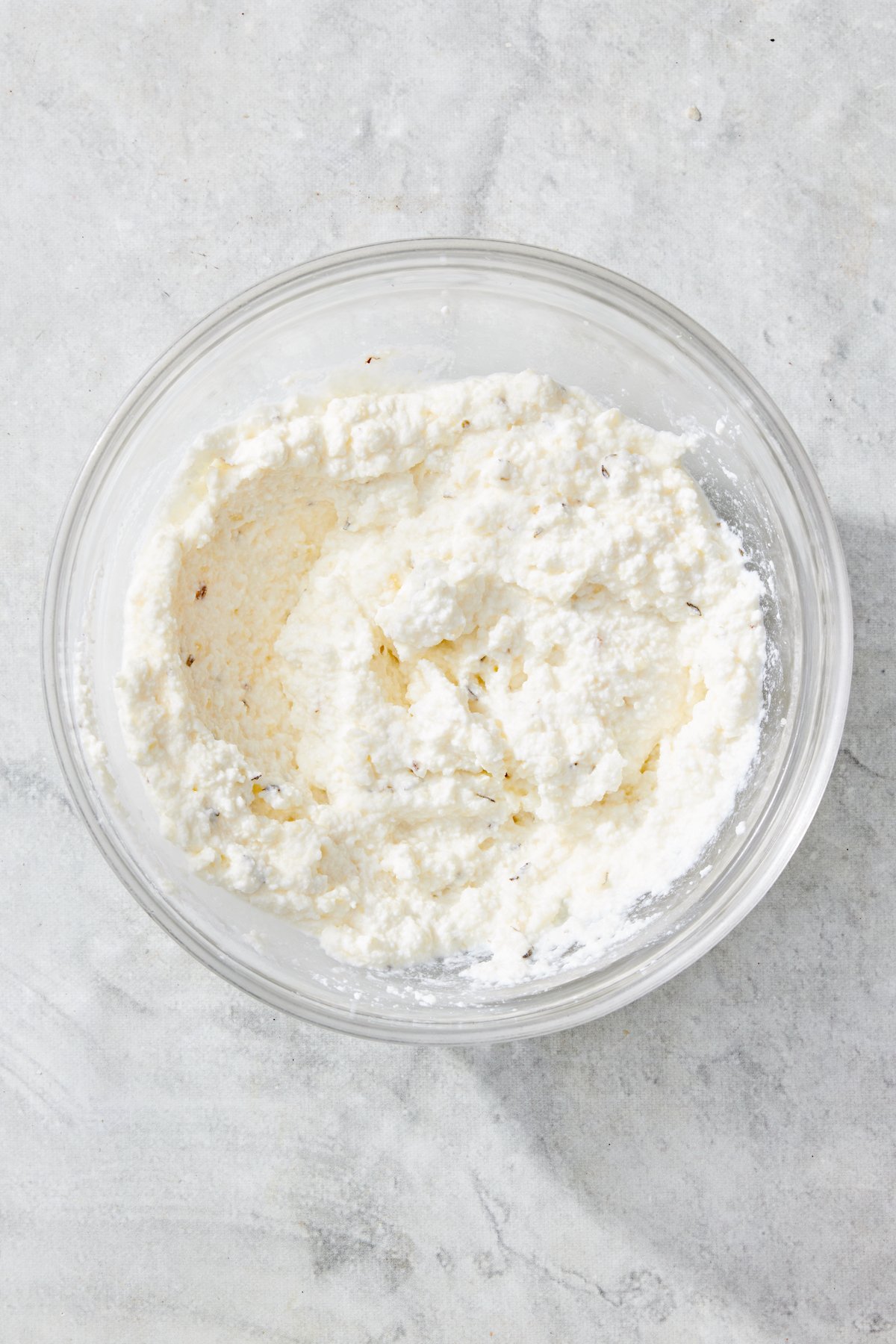 Mixture of ricotta cheese, parmesan cheese and Italian herbs in a bowl.