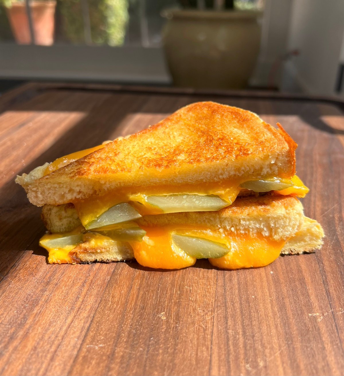 Sliced pickle grilled cheese on cutting board.