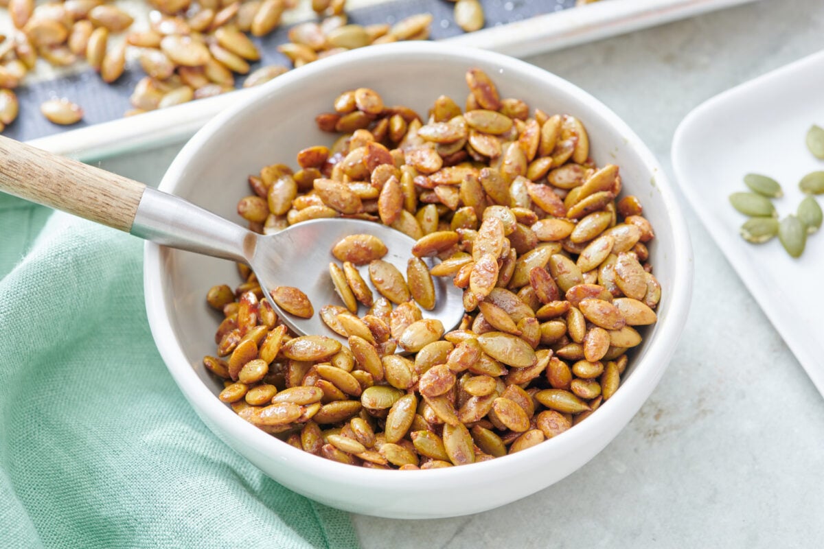 Spoon in bowl full of maple roast pumpkin seeds.