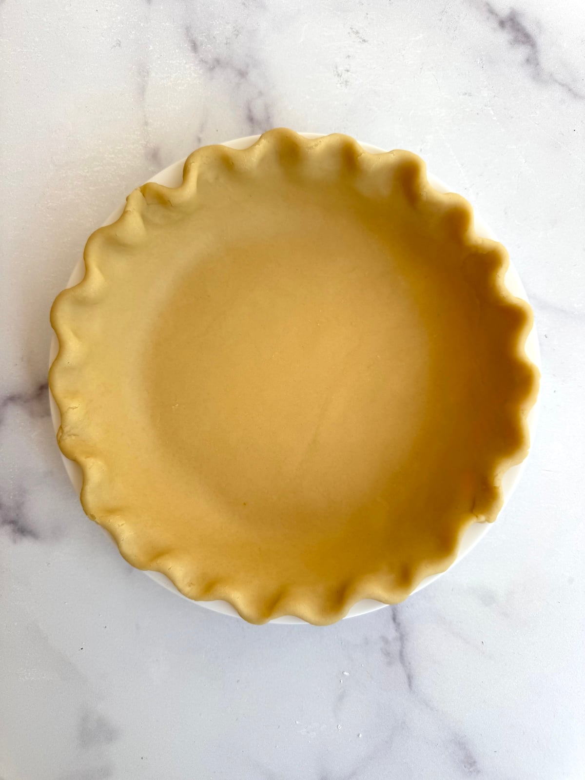 Rolled out pie dough in a pie dish.