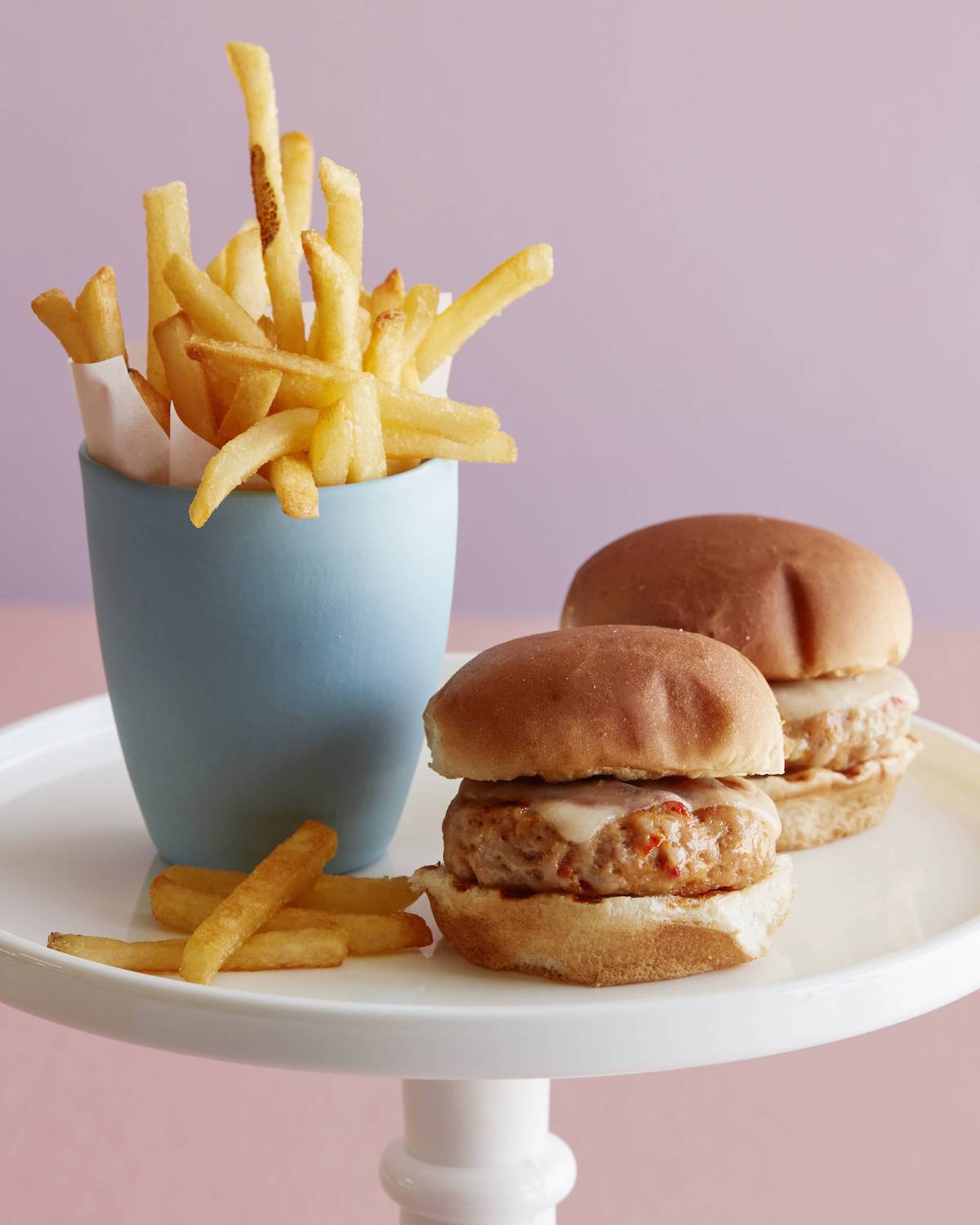 french fries and two sun dried tomato chicken burger sliders on a white platter