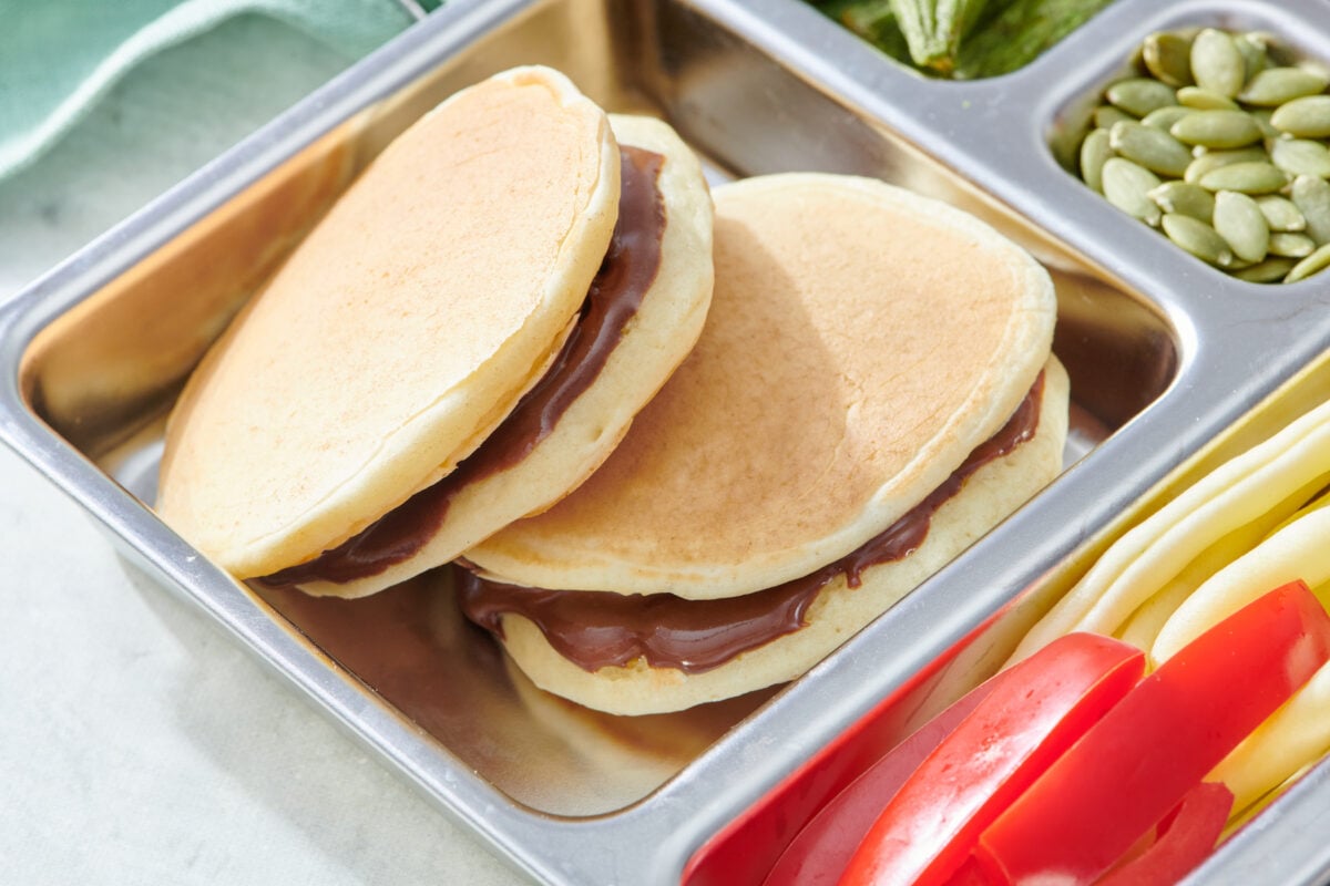 Two chocolate sunbutter pancake sandwiches in a lunchbox.