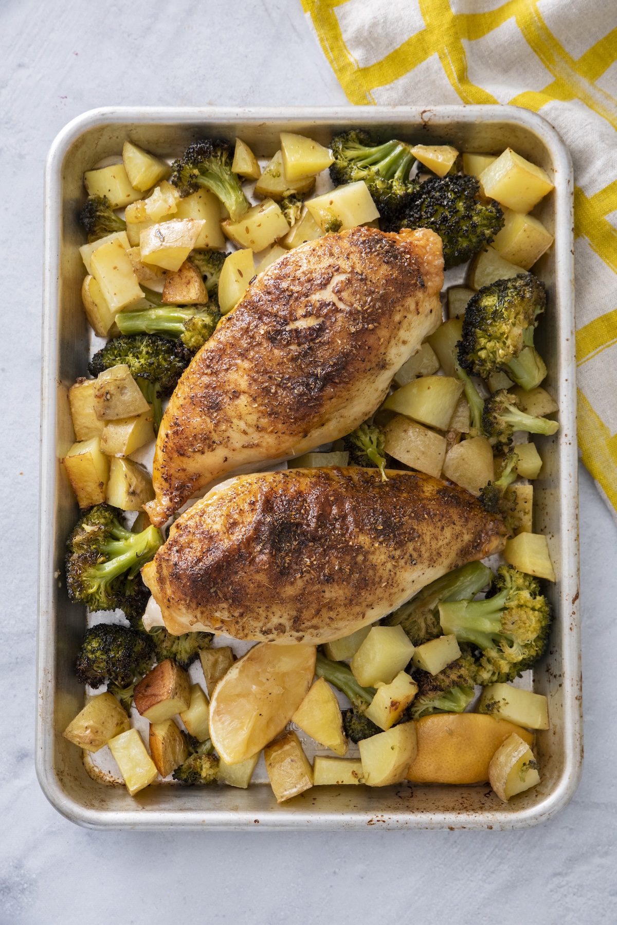 Overhead view of Middle Eastern sheet pan chicken with golden roasted chicken, broccoli, and potatoes.