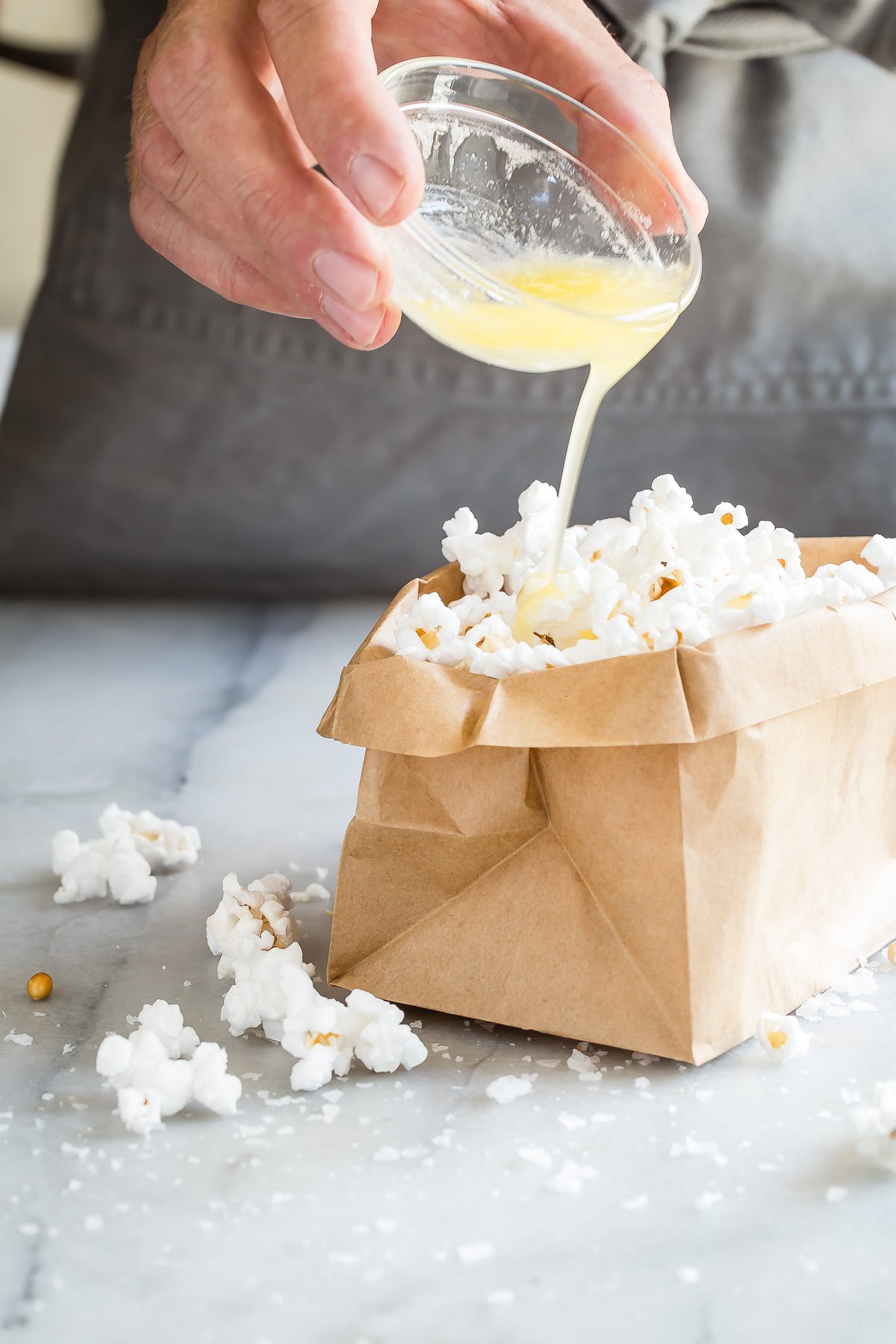 Pouring butter on paper bag popcorn.