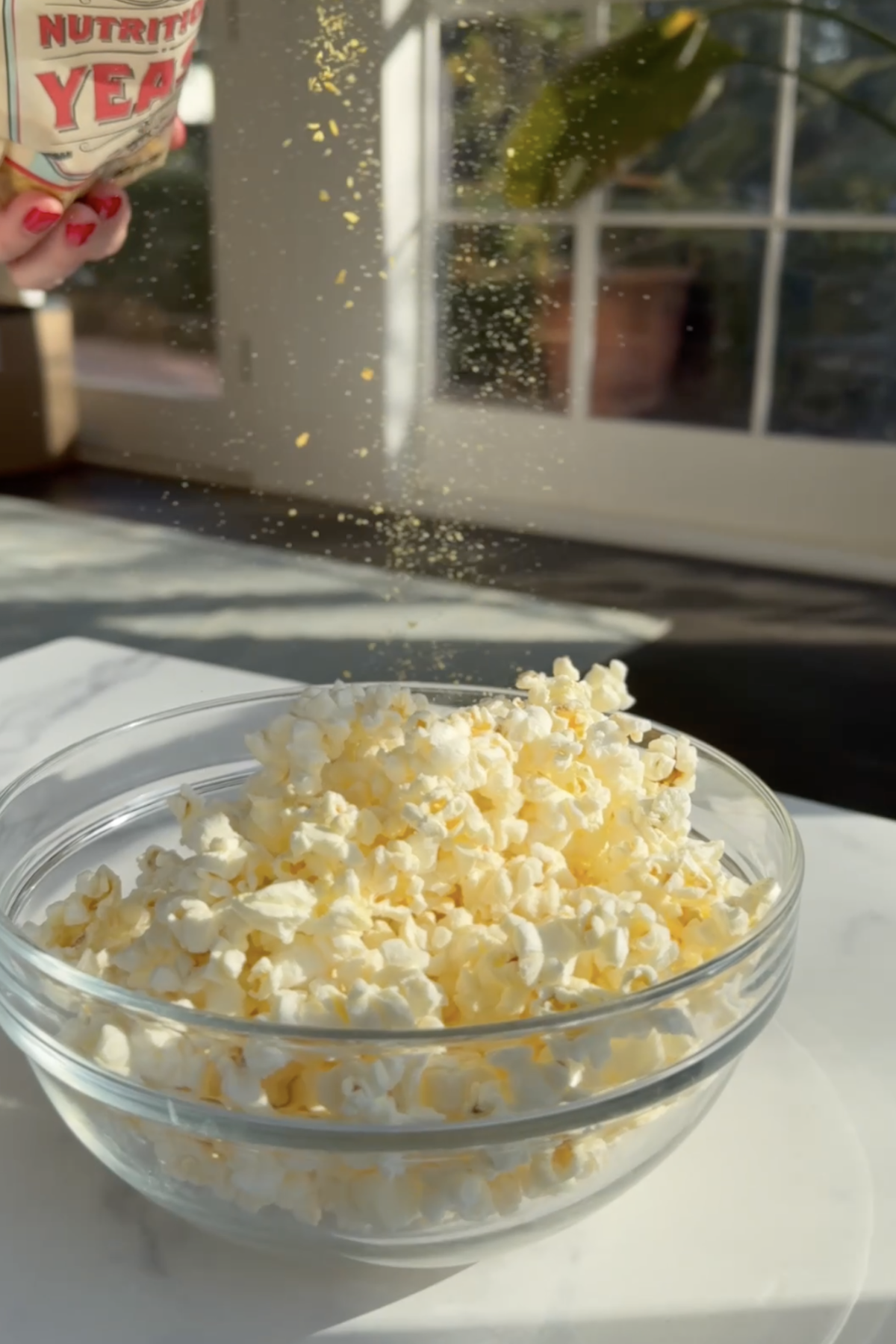 Sprinkling a bowl of popcorn with nutritional yeast.