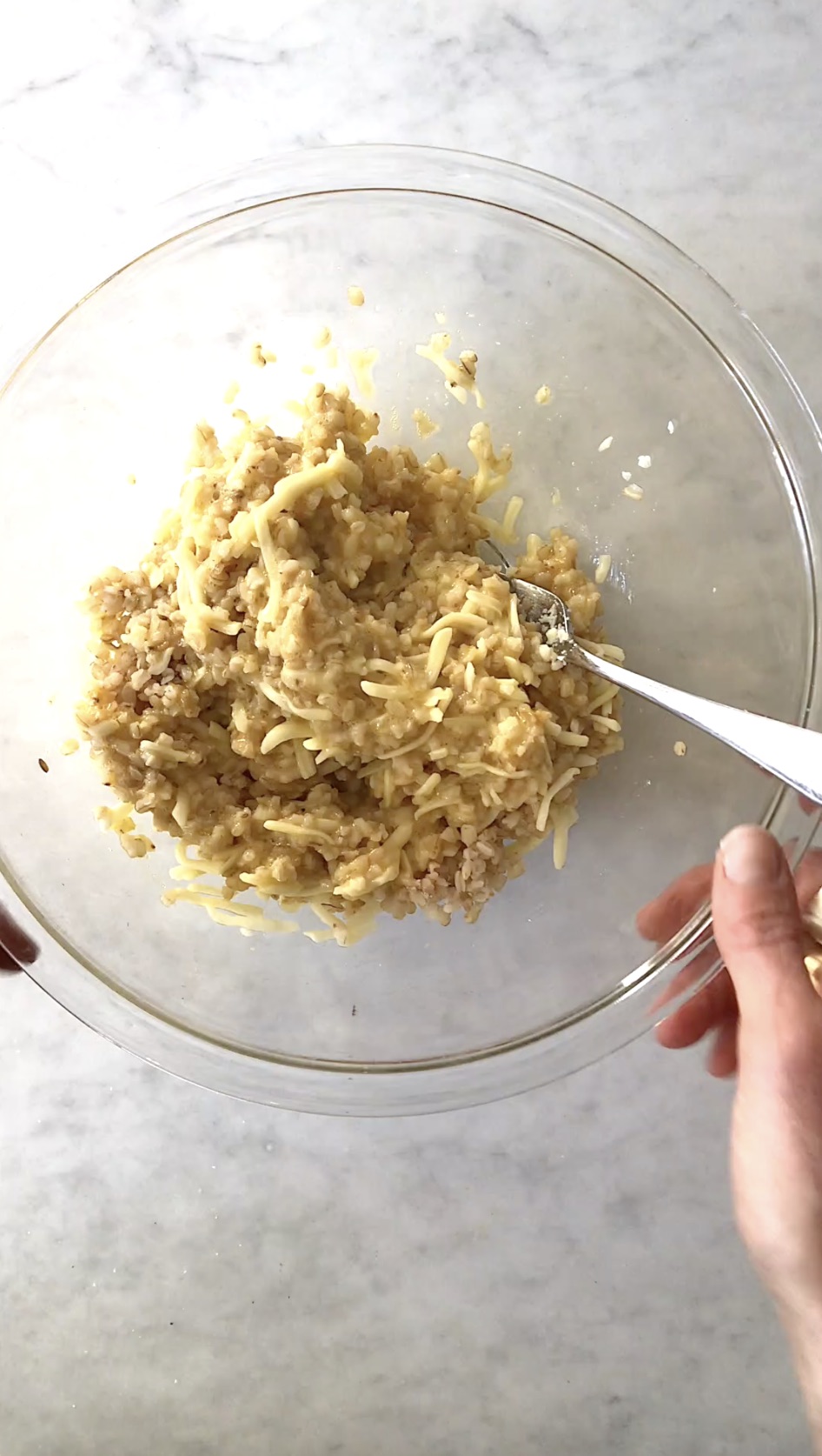 Rice, egg, and shredded mozzarella combined into a cohesive mixture in a glass bowl.