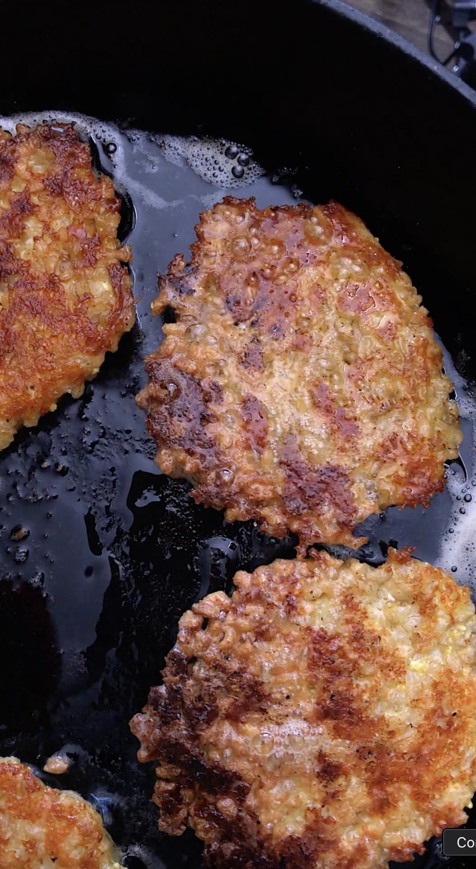 Crispy golden brown rice cake patties sizzling in a cast iron skillet.