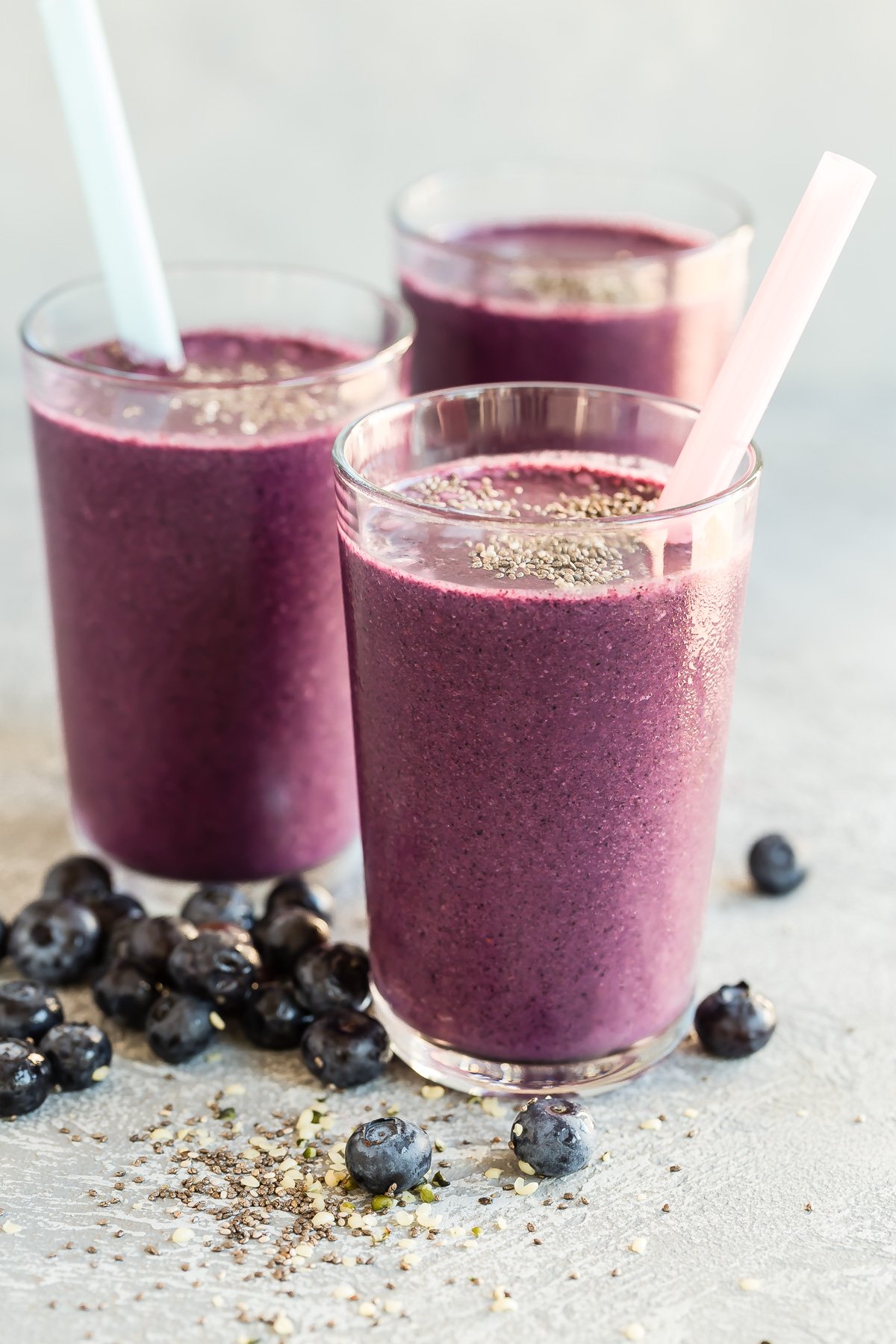 three blueberry chia smoothies in glasses with straws