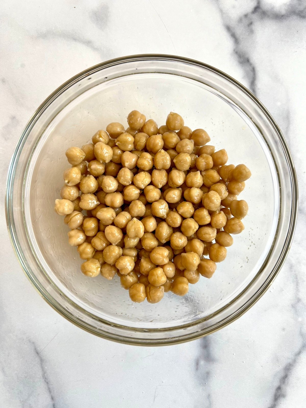 Chickpeas rinsed, drained and patted dry in glass bowl.