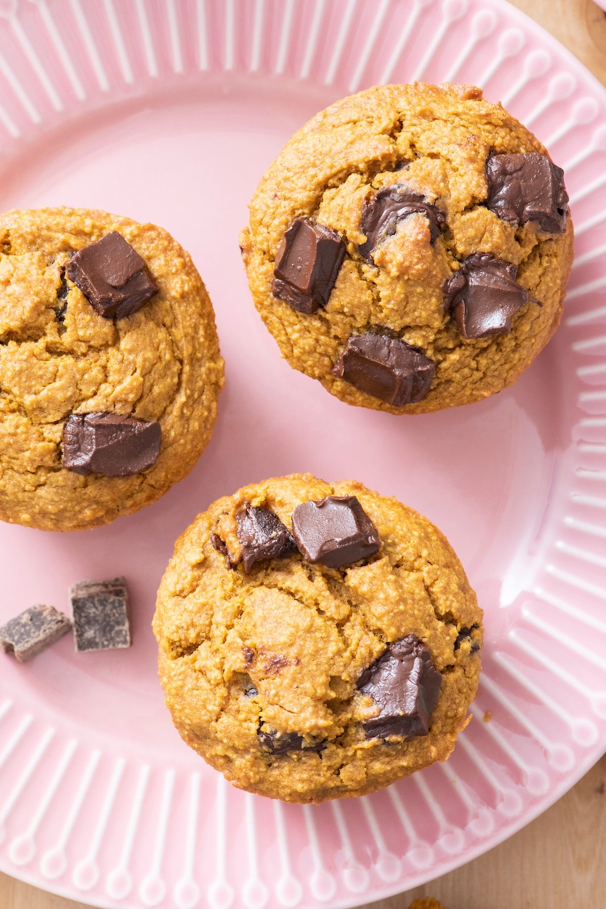 Three flourless pumpkin chocolate muffins on a plate.