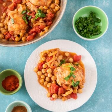 Easy Moroccan chicken with chickpeas and tomatoes served on a white plate alongside the pan.