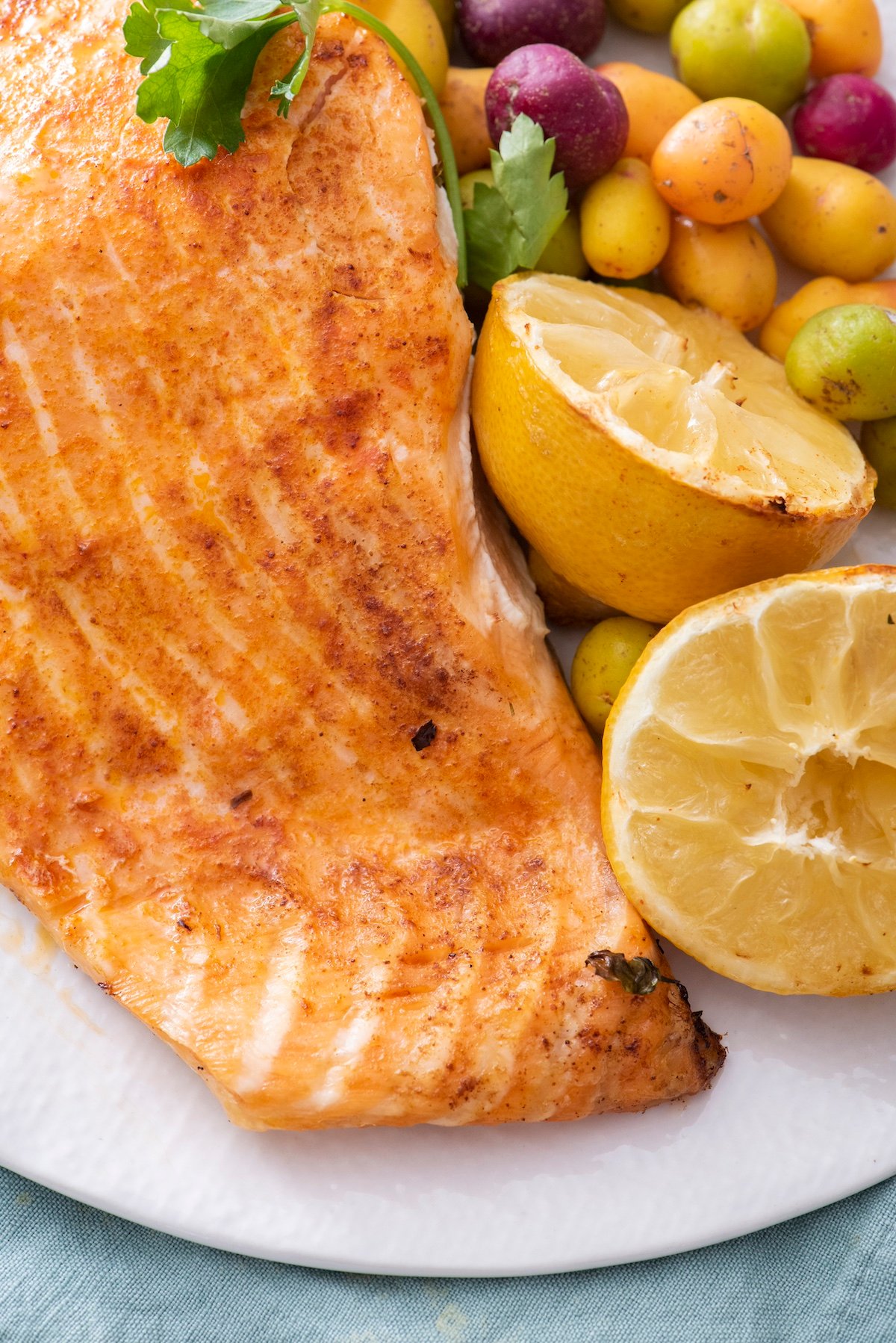 Air fried salmon on a plate with potatoes and lemon slices.