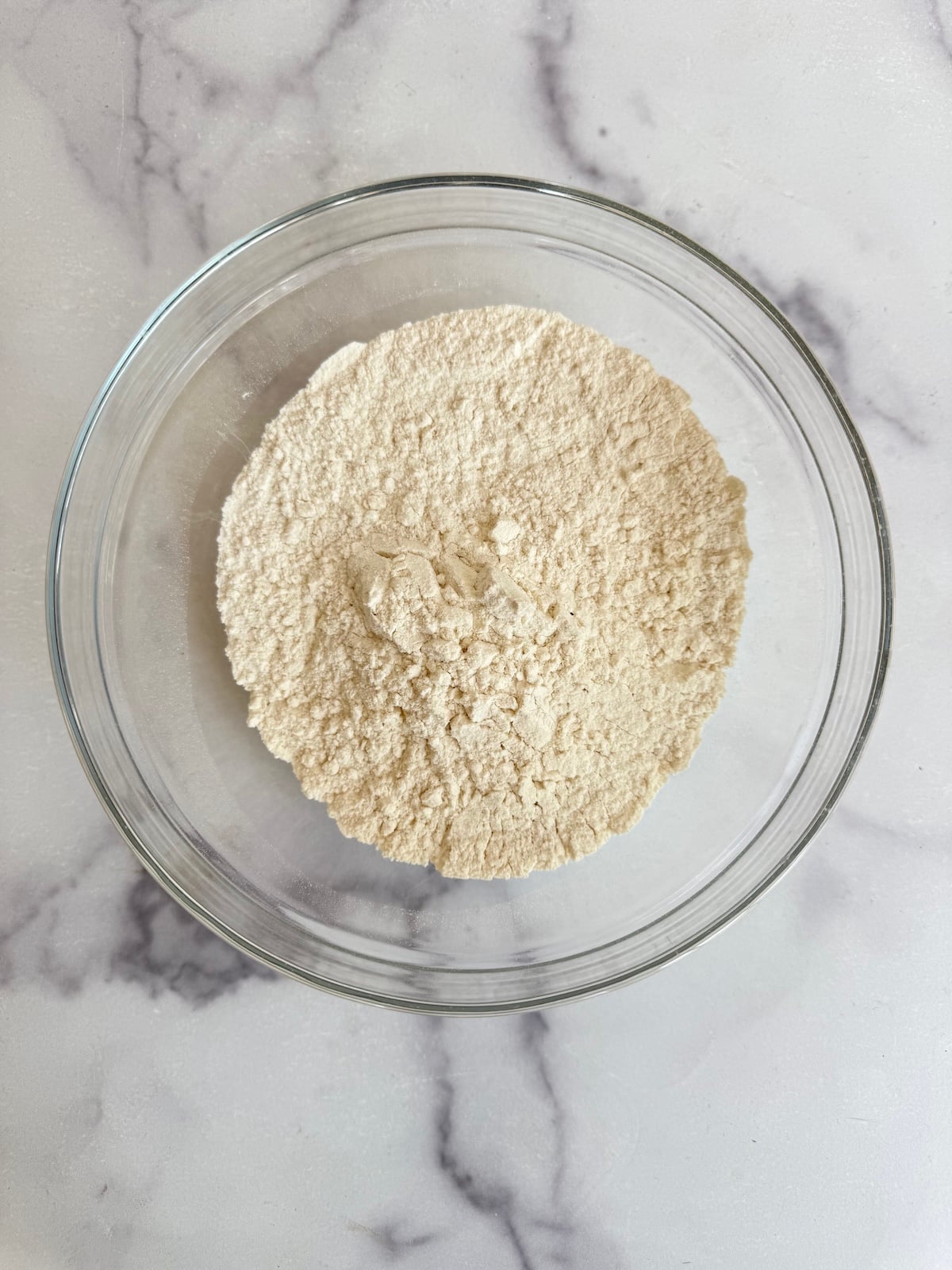 Sifted flour, baking powder, and salt combined in a glass bowl for blackberry tea cake.