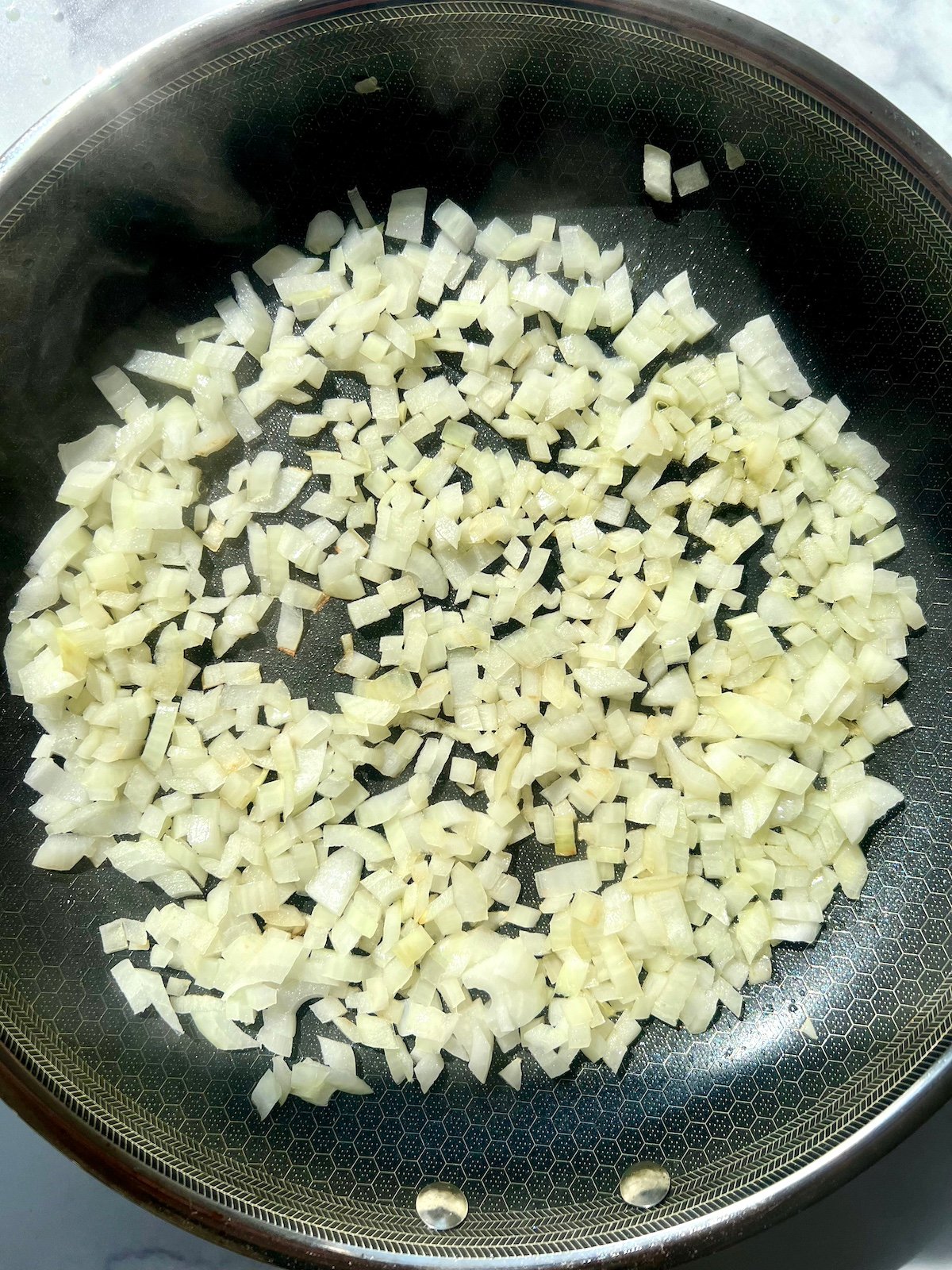 Onions cooking in a sauté pan.