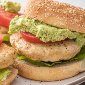 A juicy turkey burger on a sesame bun with guacamole, tomato, and lettuce.
