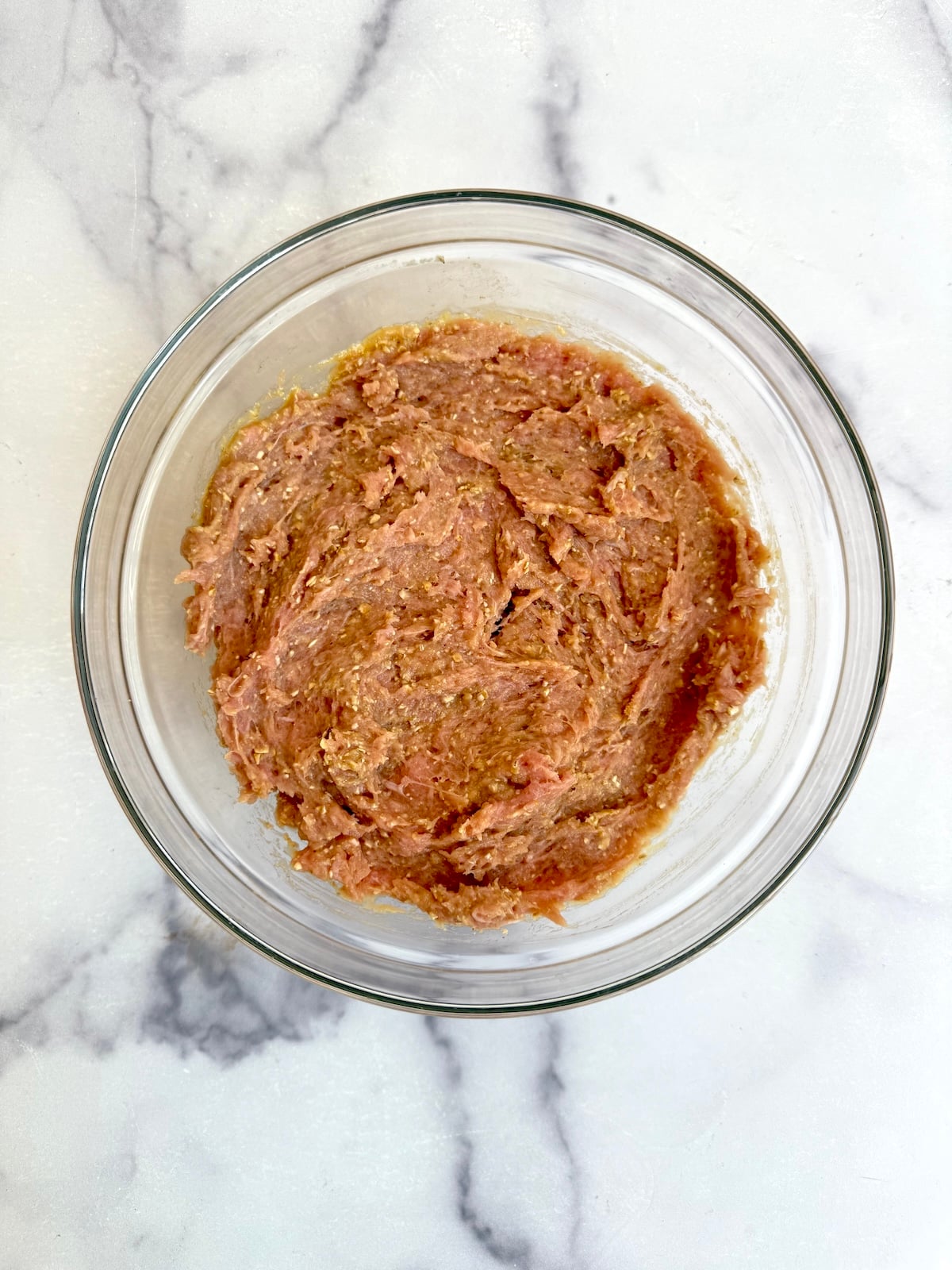 Ground turkey mixture with oats, egg, and spices combined in a glass bowl.
