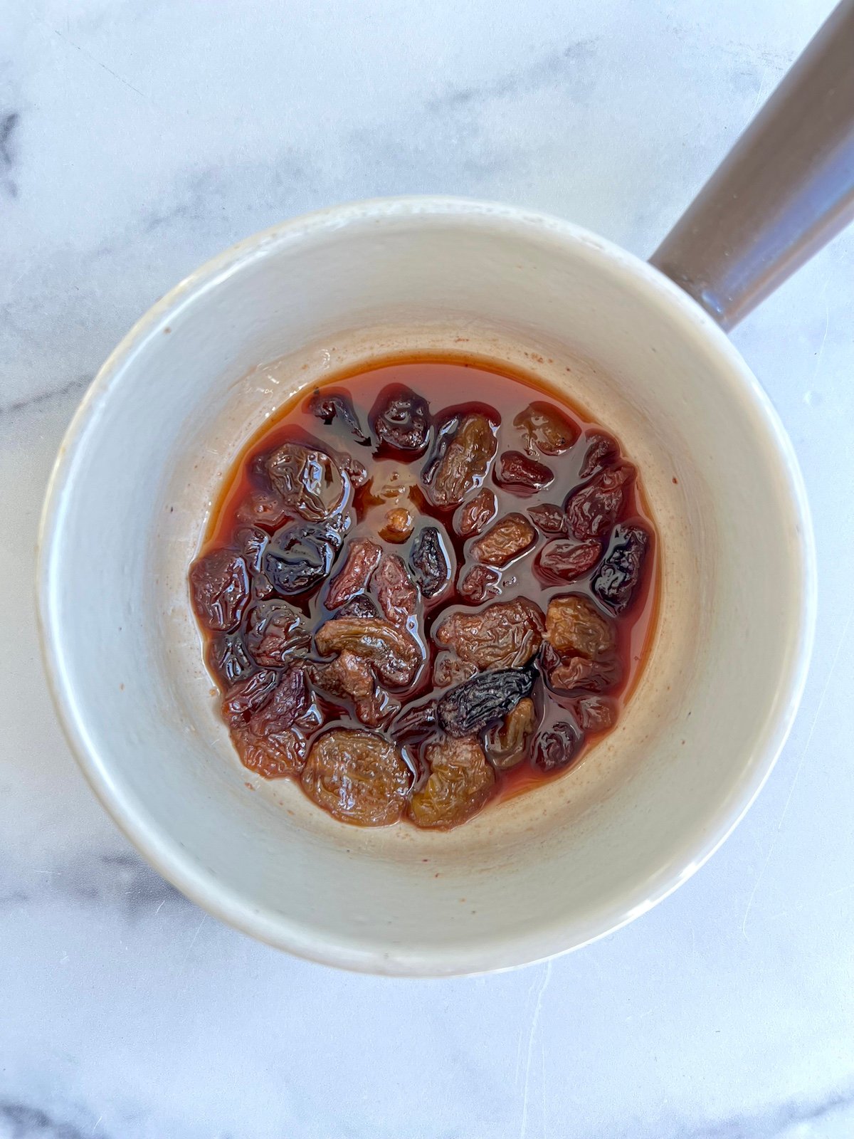 Red wine vinegar, honey, raisins and salt simmering in sauce pan.