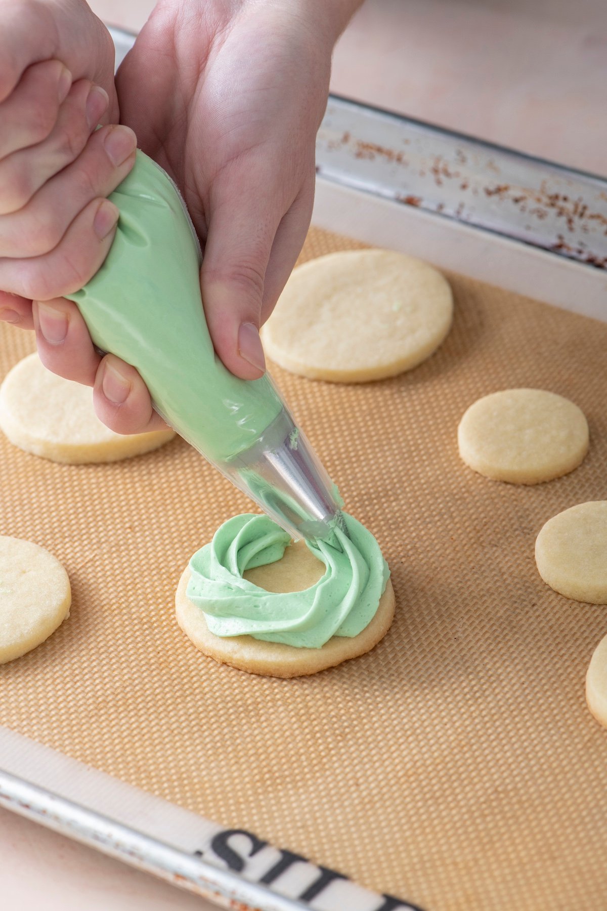 Piping buttercream icing onto sugar cookie.