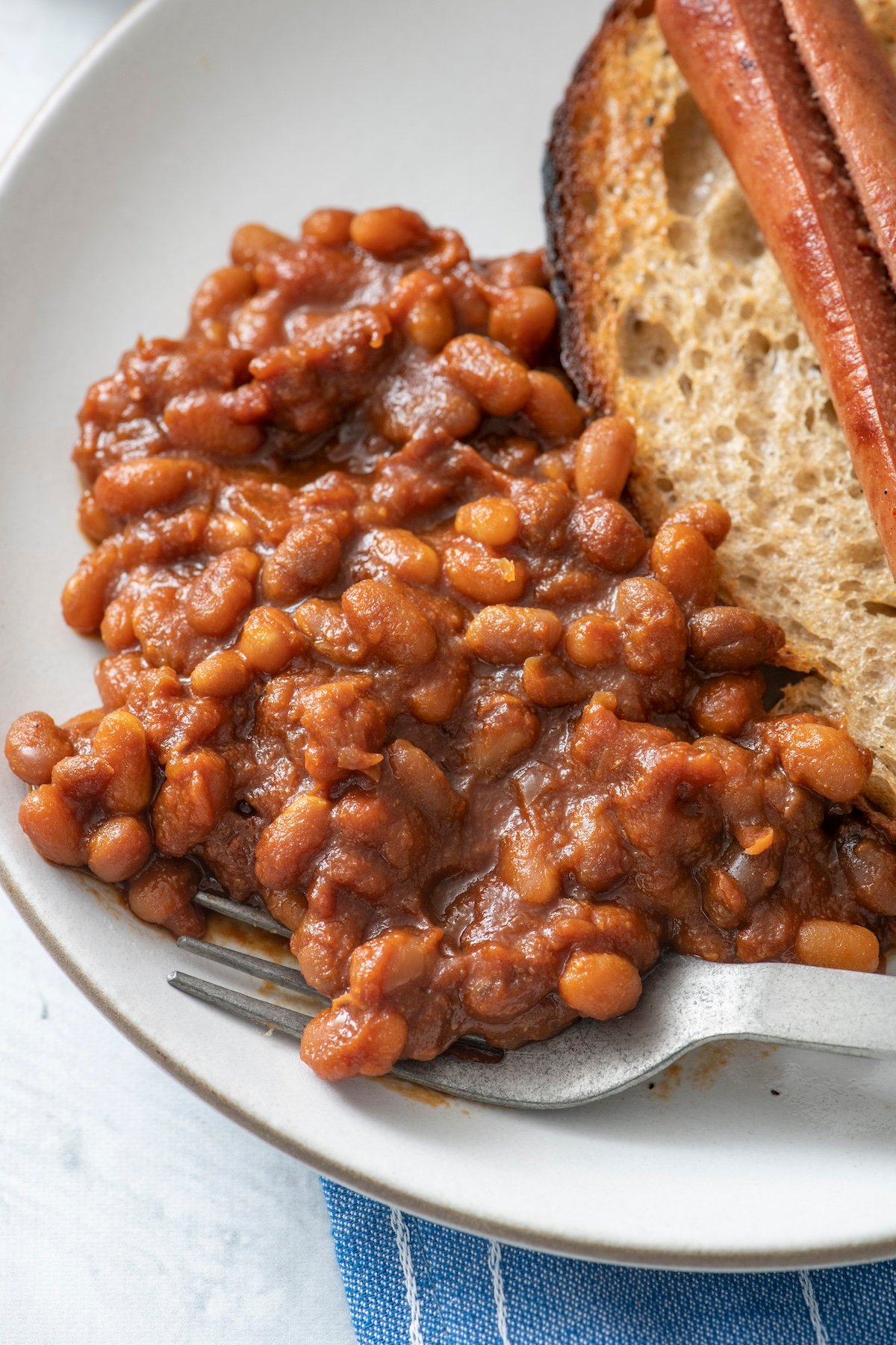 Baked beans on a plate served with a hot dog.