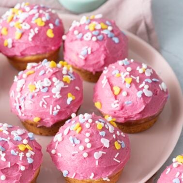 Pink cupcakes with frosting on serving plate.