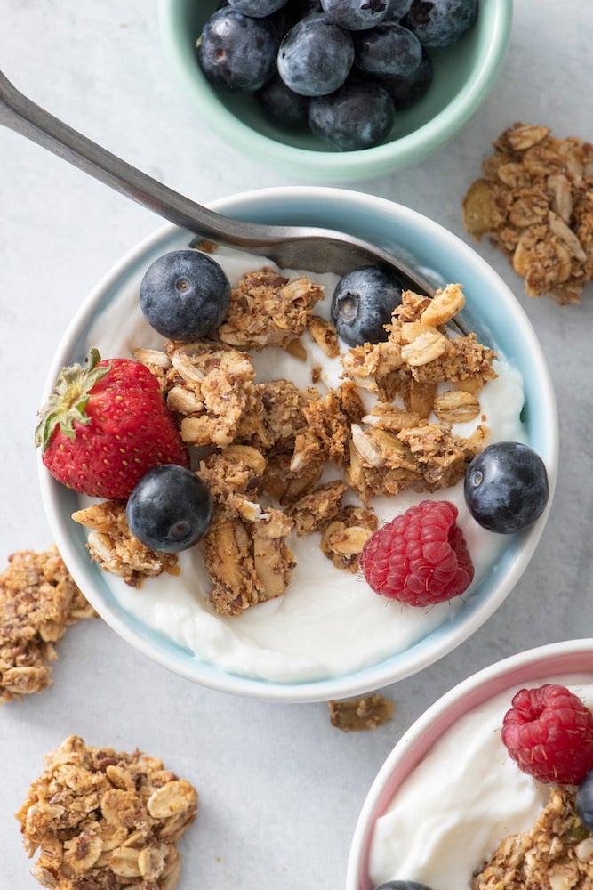 Yogurt in a bowl topped with granola and berries