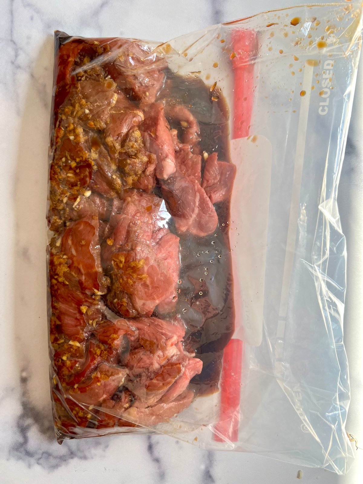 Skirt steak marinating in clear plastic bag.