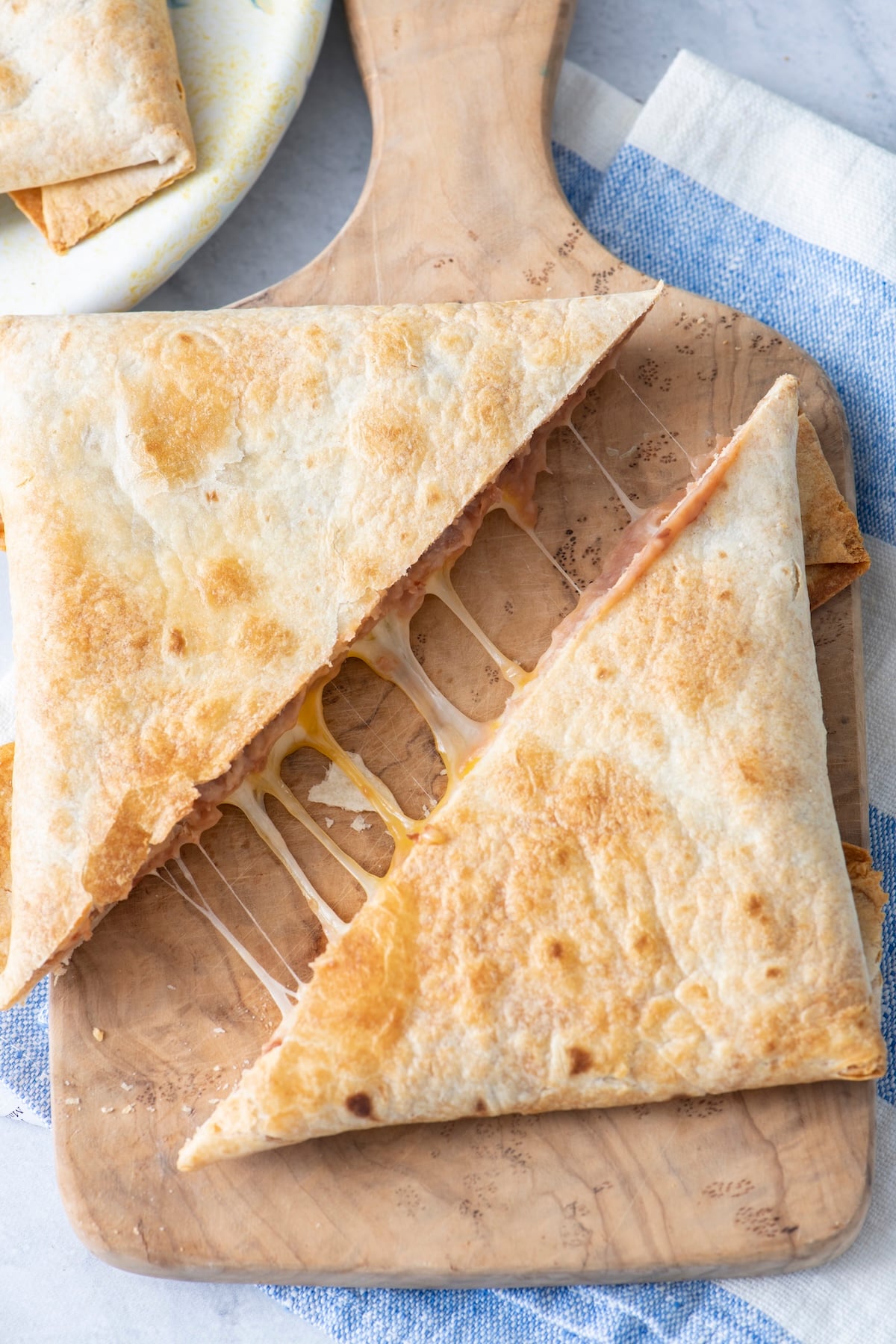 Air fryer tortilla pillow cut in half on a cutting board.