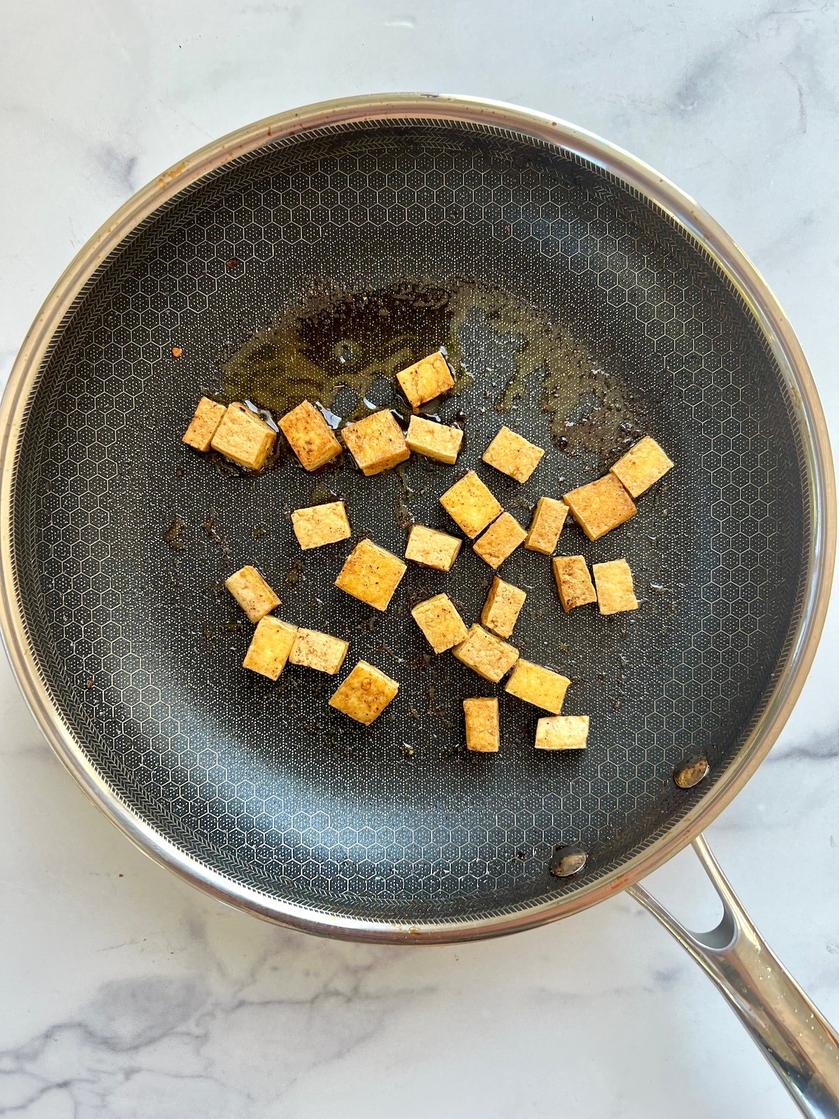 Sautéing tofu with taco seasoning in pan.