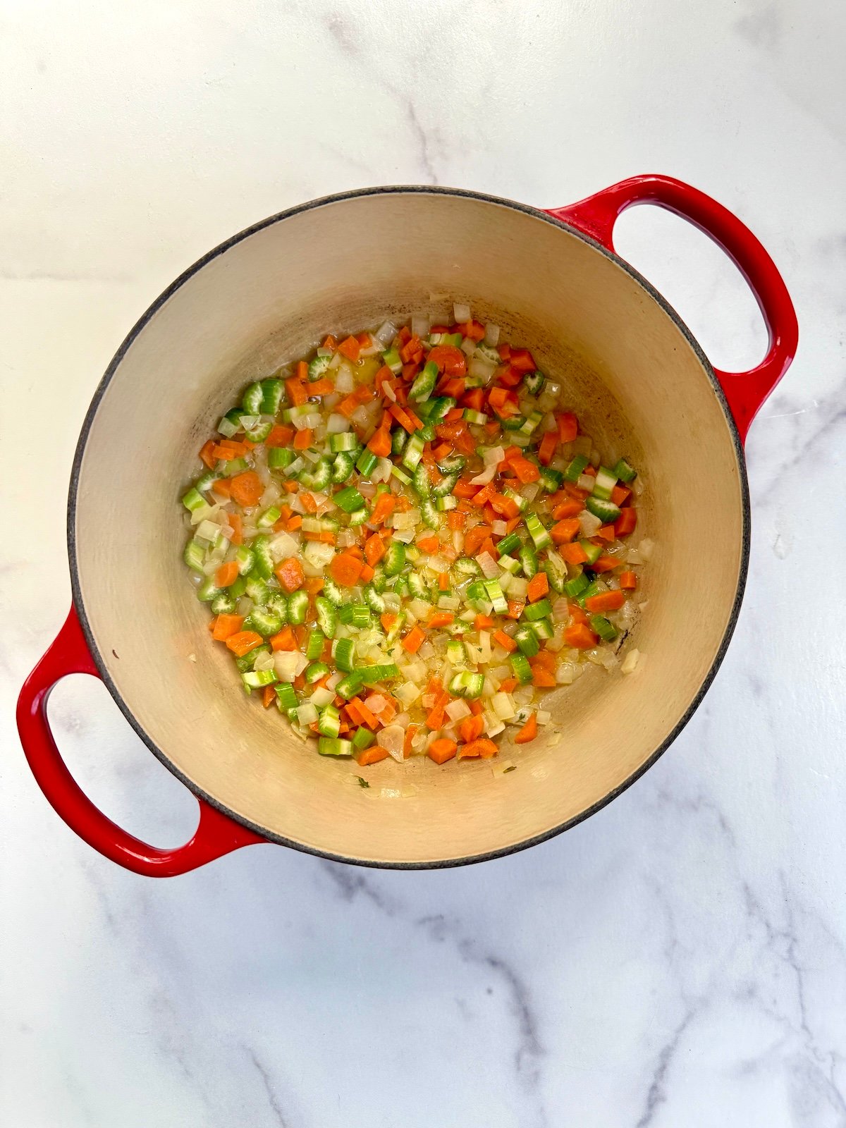 Celery, carrots, onion and thyme sauteeing in a stock pot.