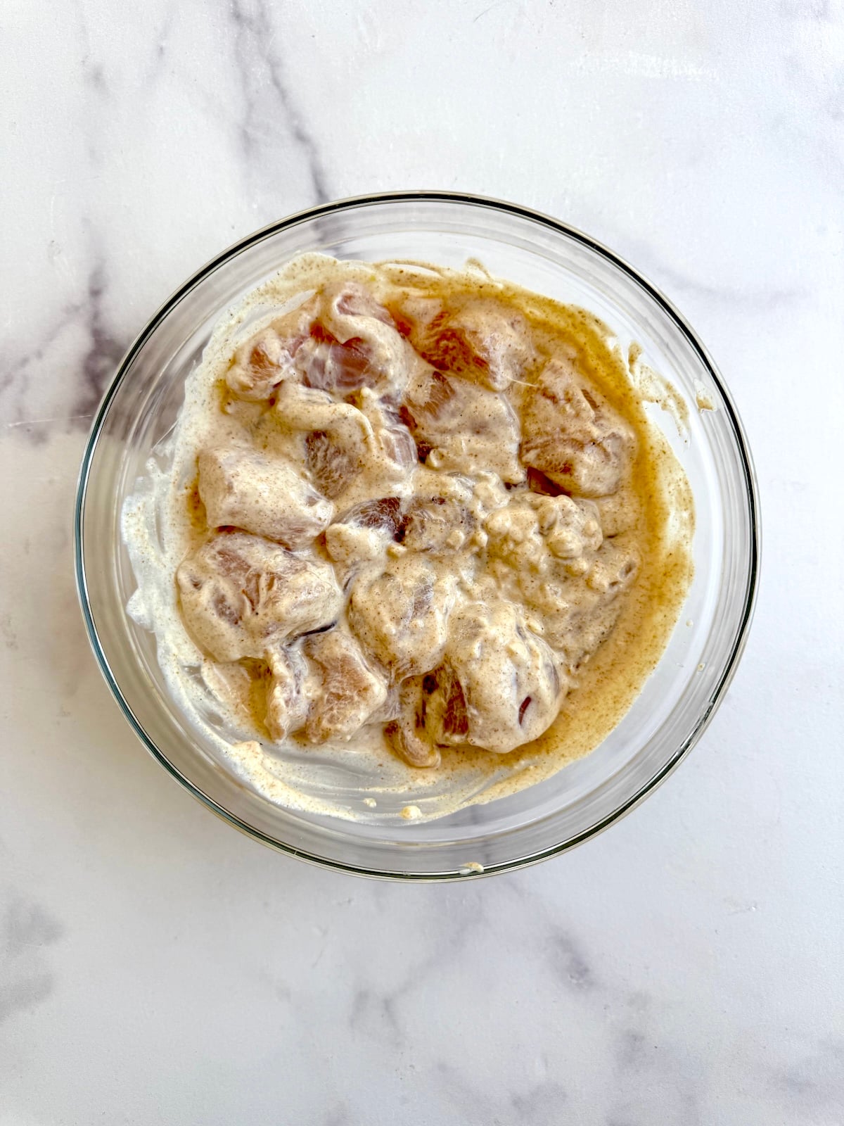 Chicken breast cubes marinating in yogurt mixture.