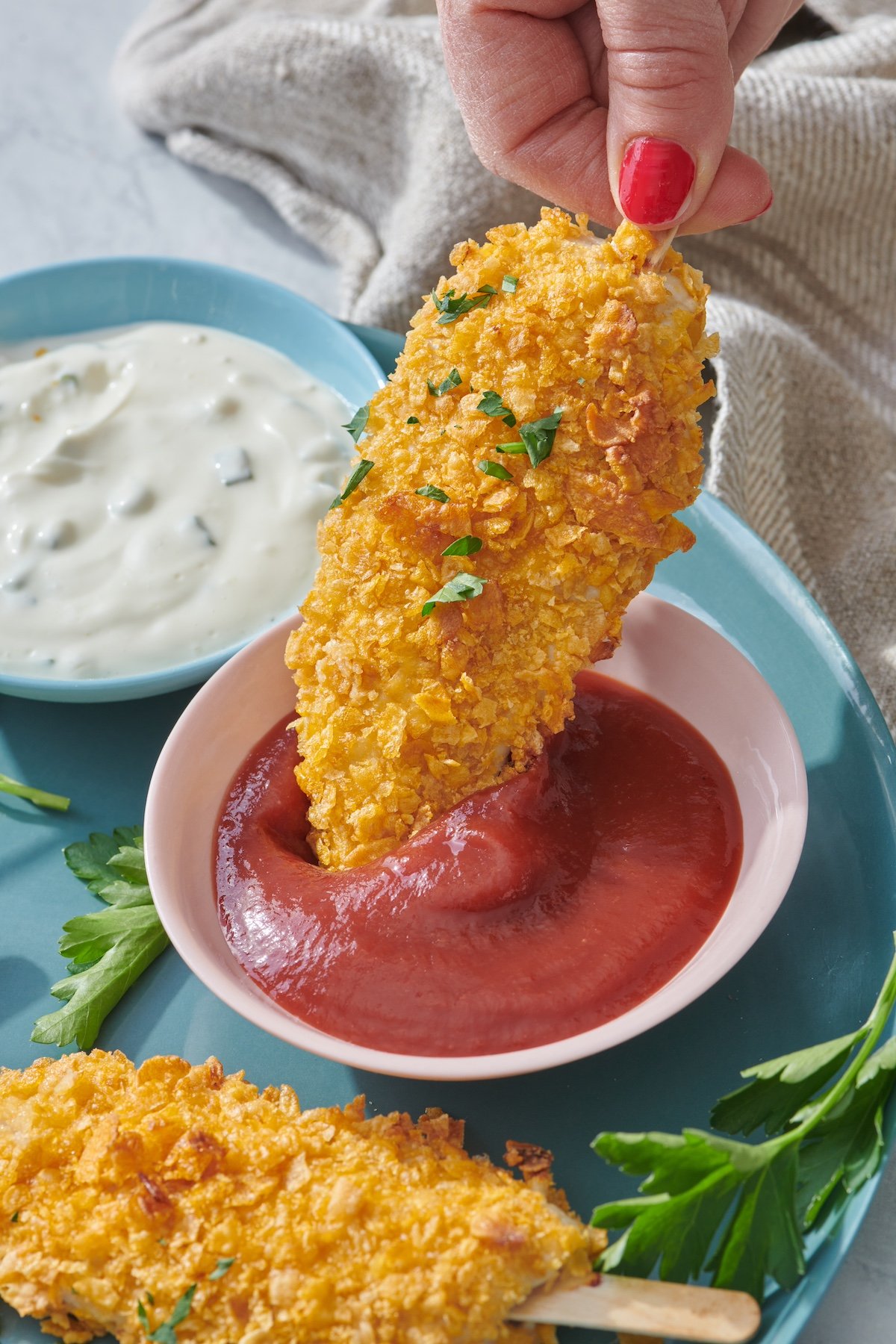 Dipping chicken on a stick in ketchup.