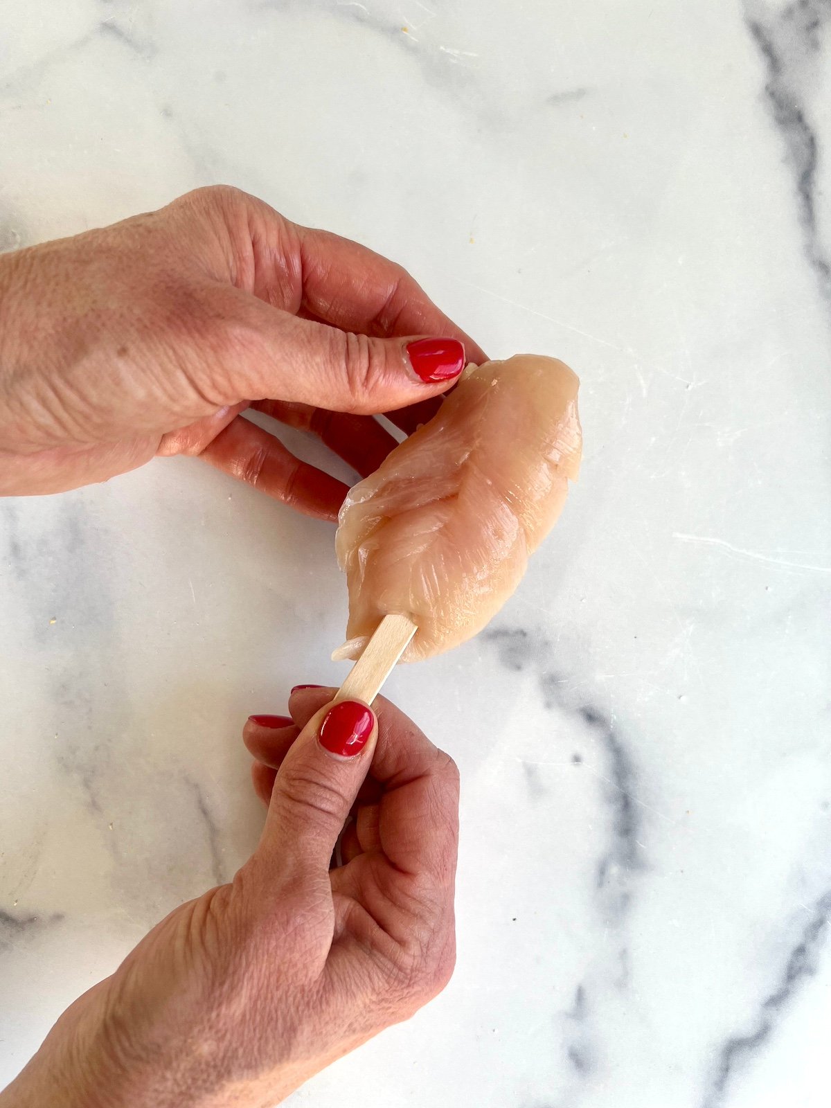 Skewing a popsicle stick into a chicken tender.