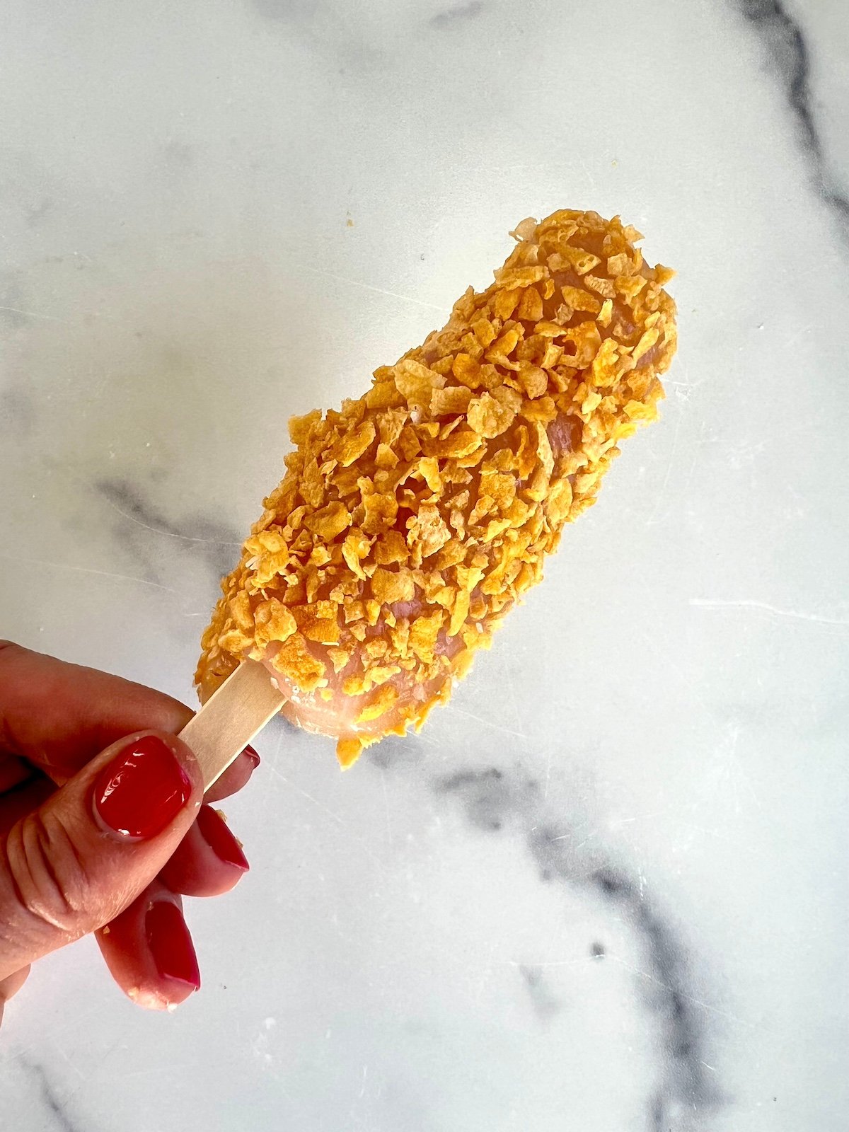 Breaded chicken on a stick ready to be baked.