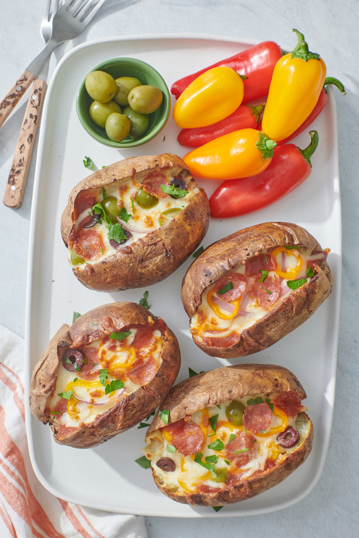 serving platter with baked potatoes topped with pizza toppings
