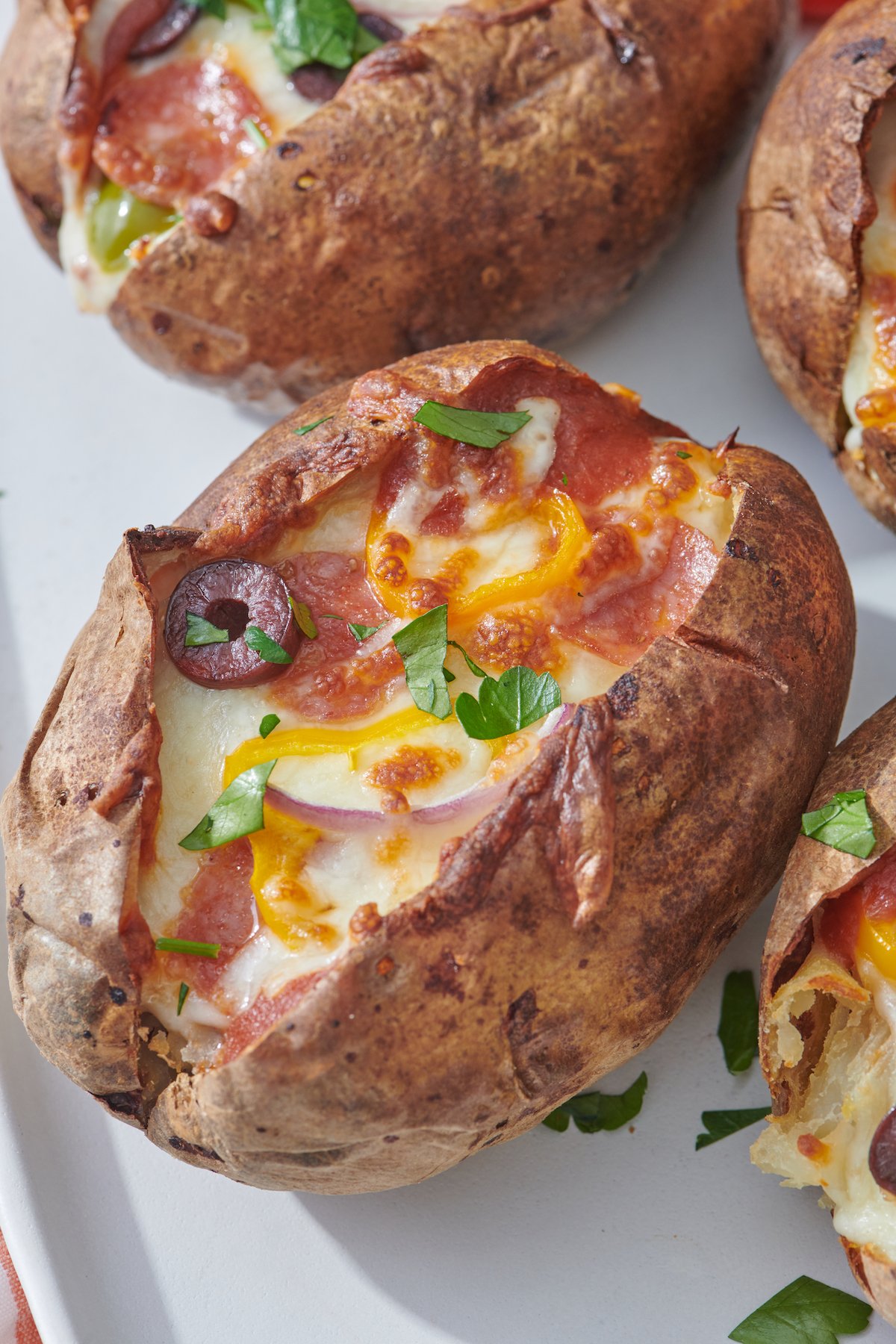 close up of pizza stuffed potato with pepperoni, red onions, olive and yellow pepper